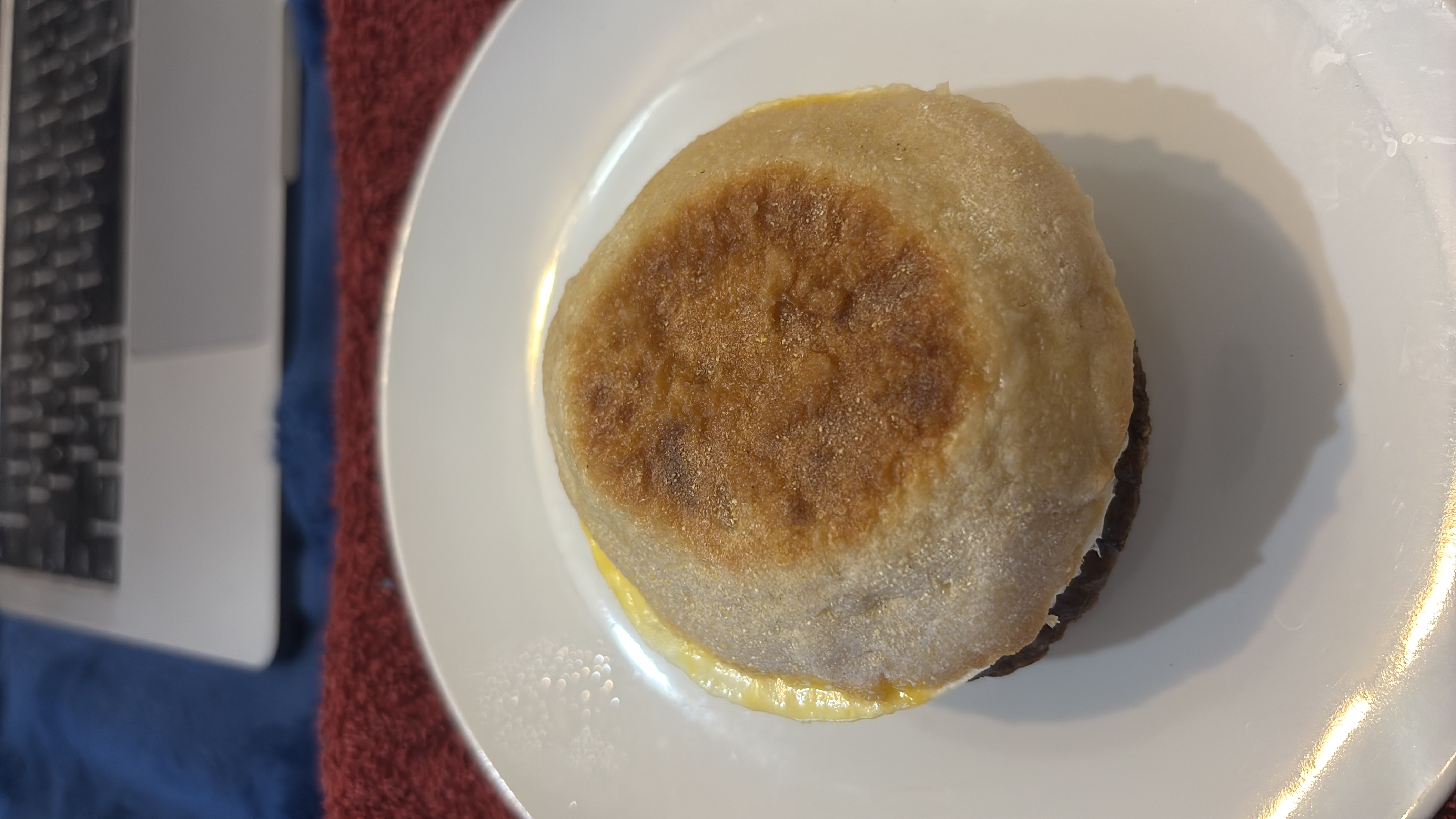 A breakfast sandwich consisting of an English muffin, egg, and sausage patty, providing a balanced mix of protein, carbs, and fats.