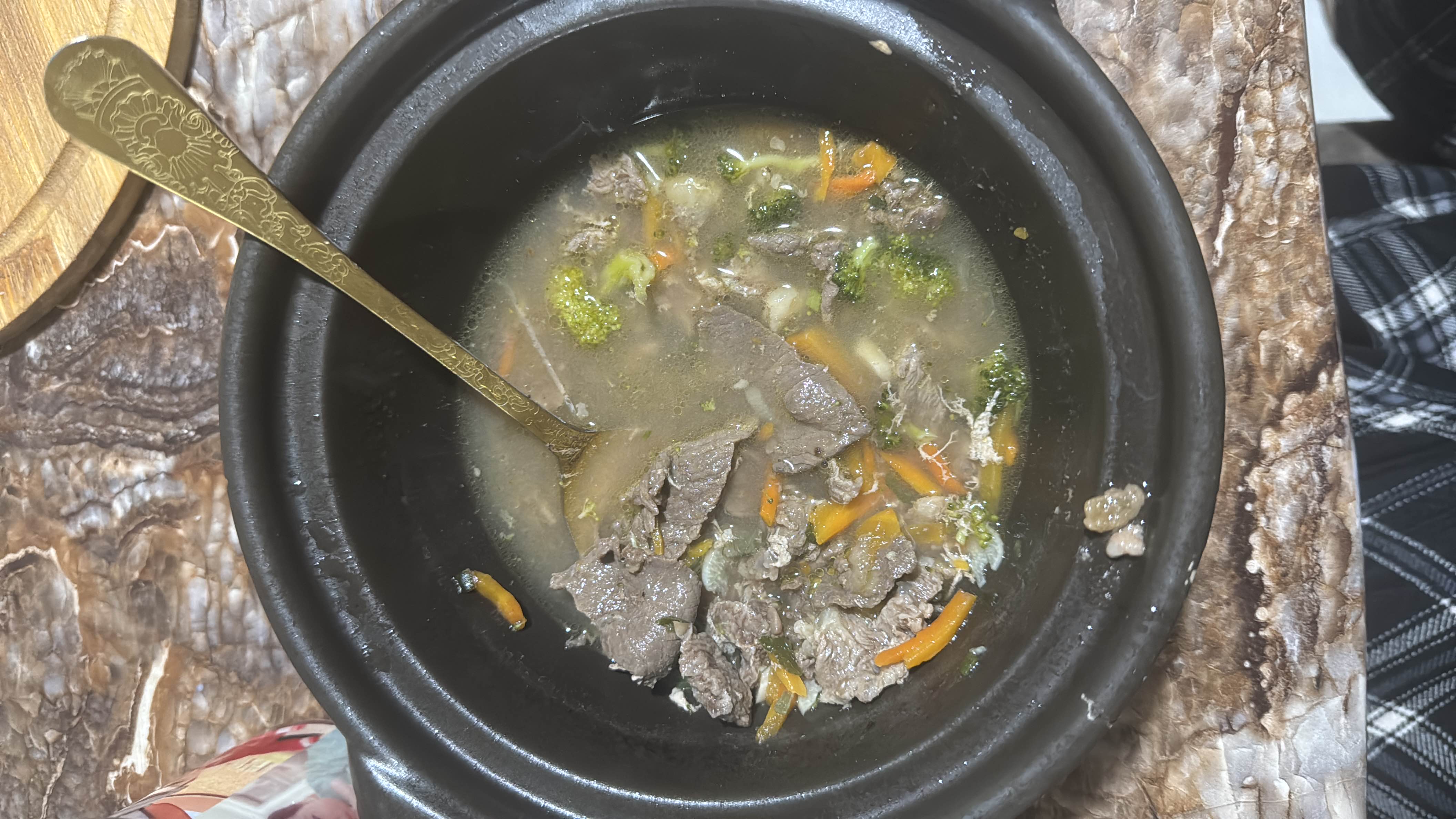 A nutritious beef and vegetable soup containing beef slices, broccoli, and carrots in a light broth.