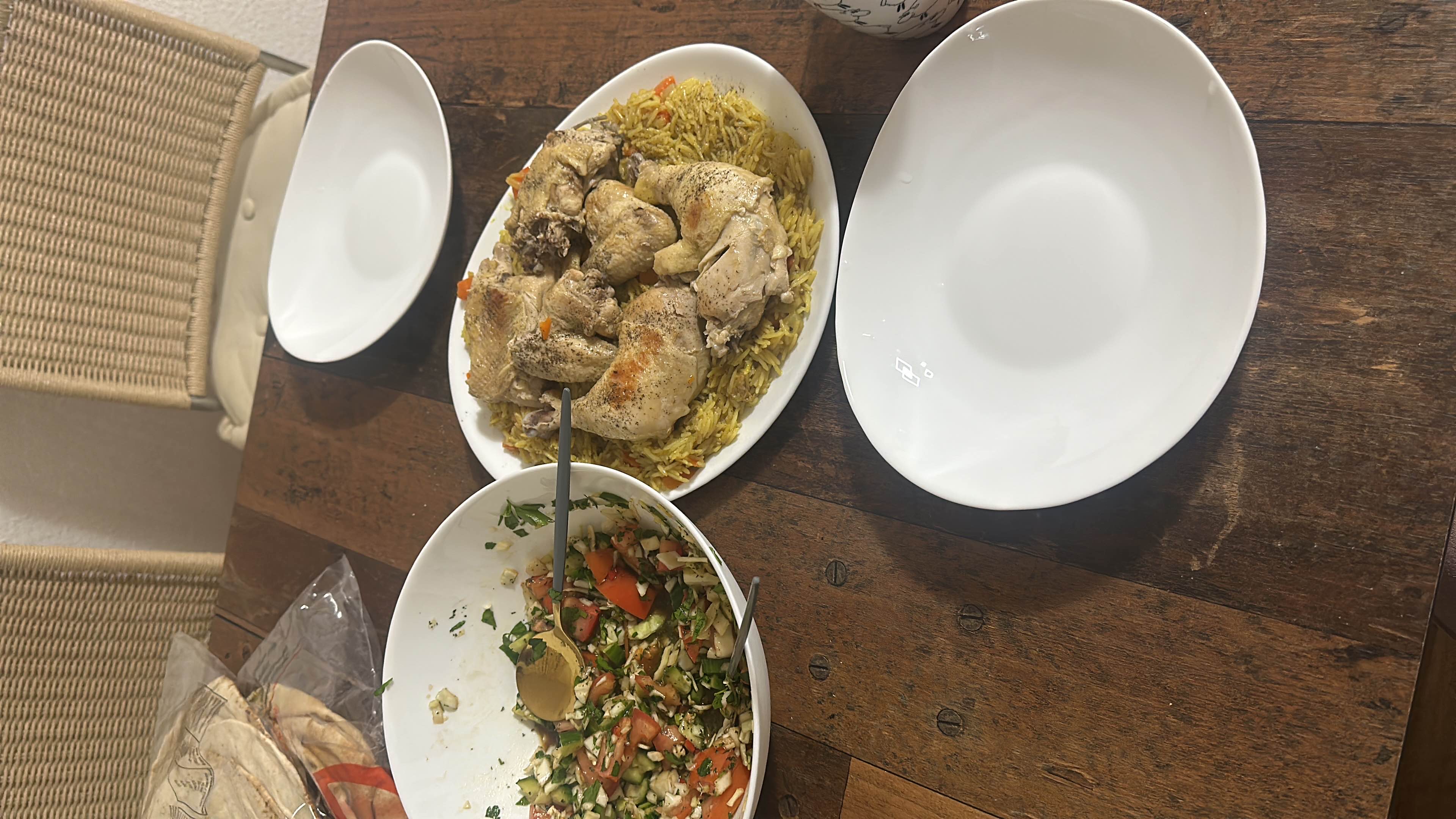 A meal consisting of seasoned chicken served over spiced rice, accompanied by a fresh vegetable salad.
