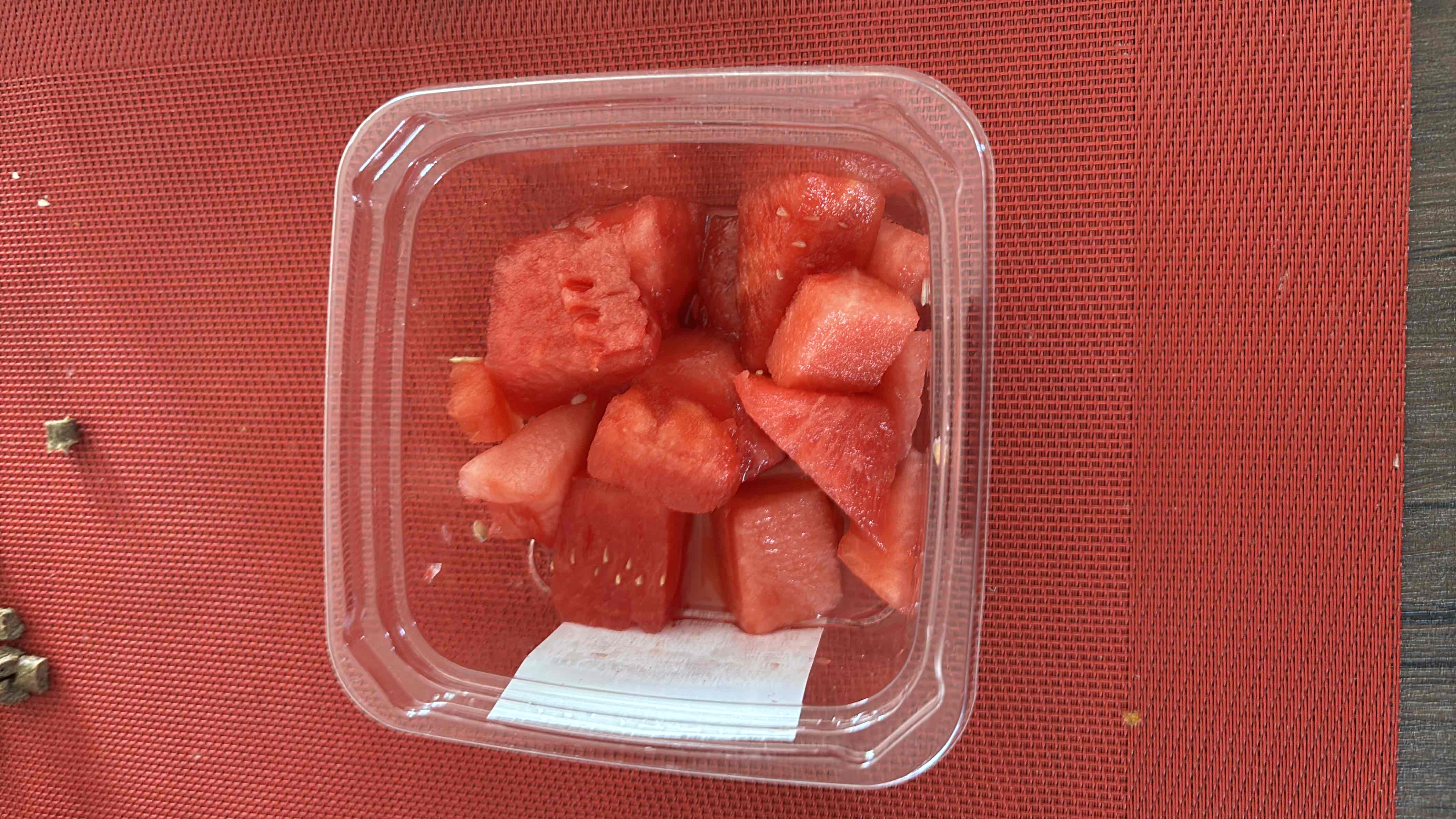 The image shows a container of fresh watermelon cubes, which are low in calories, high in water content, and provide a refreshing snack option.