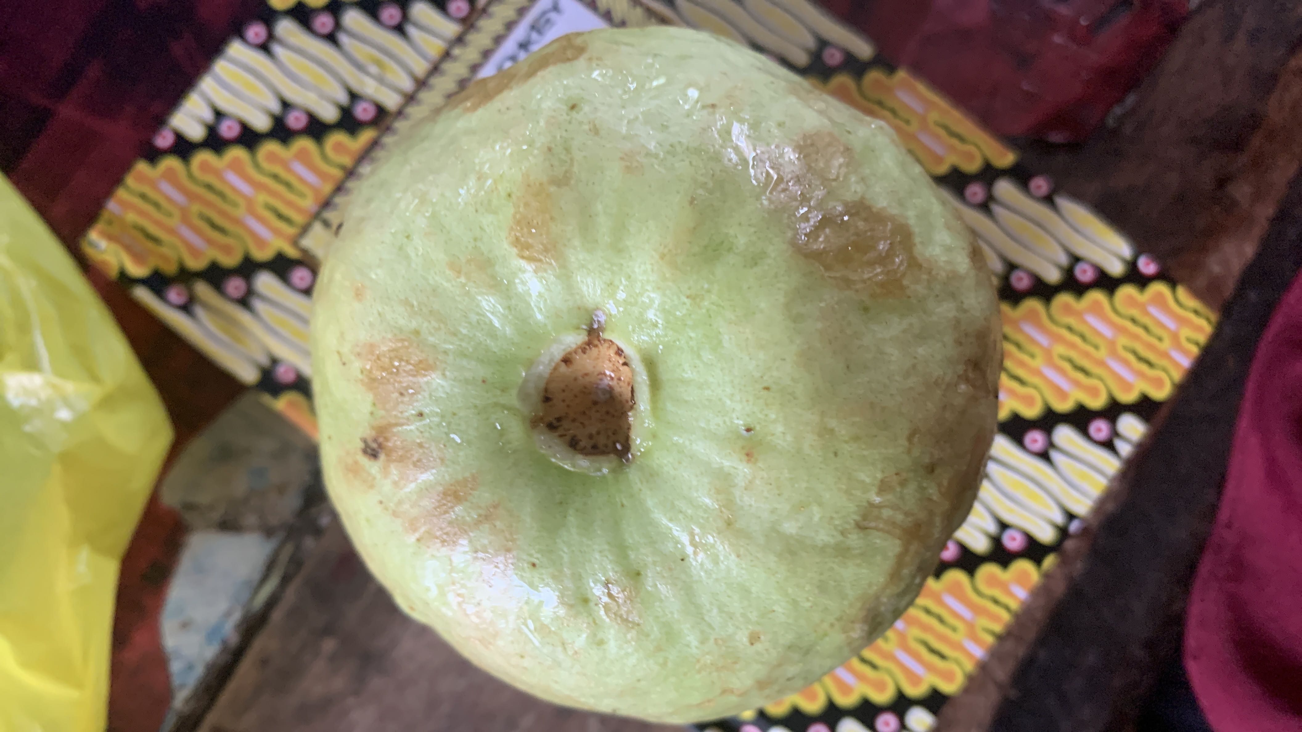 The image shows a guava, a tropical fruit that is low in calories and rich in vitamins, making it a healthy snack option.