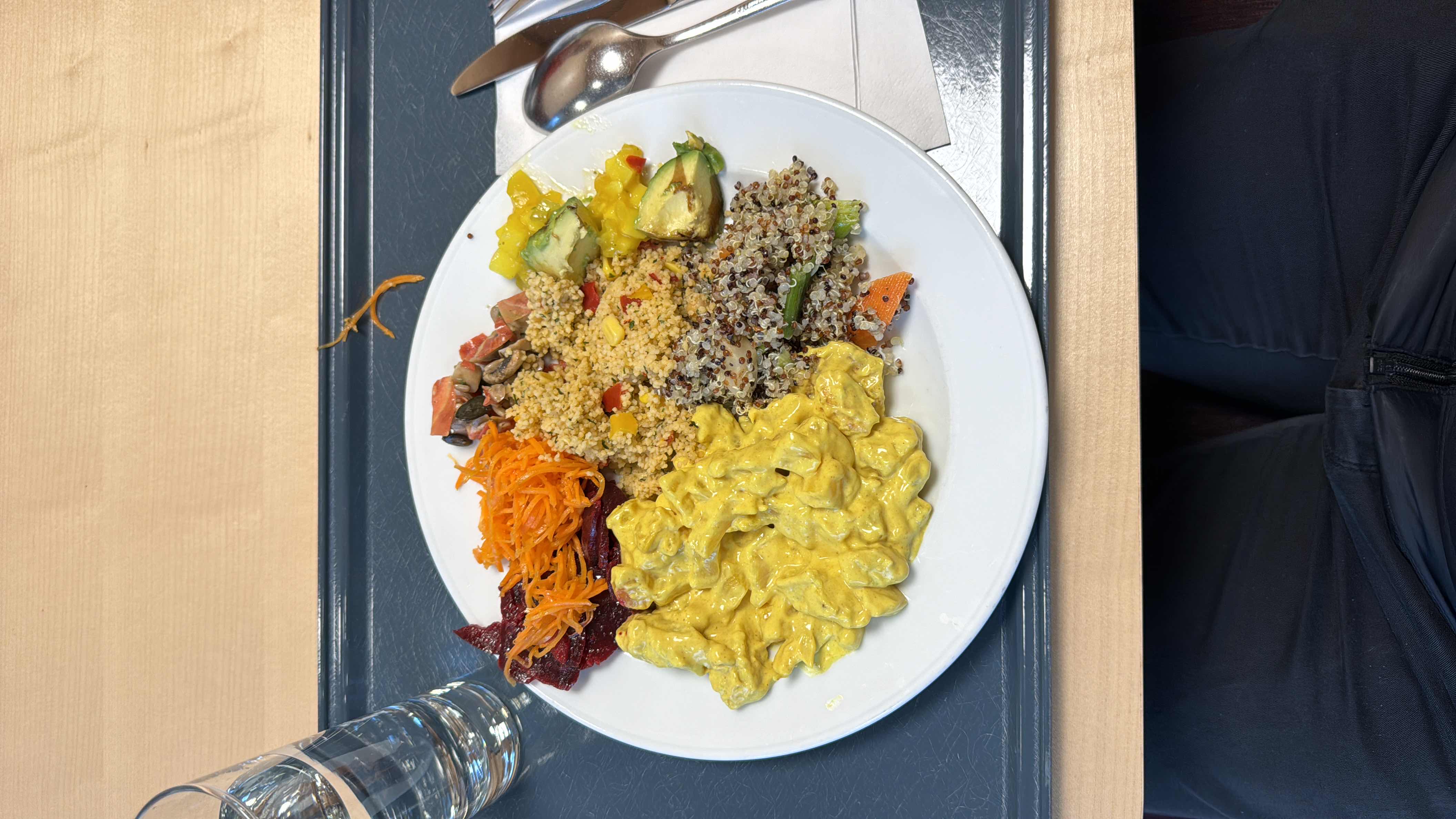 A hearty chicken curry with quinoa and couscous, complemented by avocado, mango, and a variety of vegetables, offering a balanced mix of protein, carbohydrates, and healthy fats.