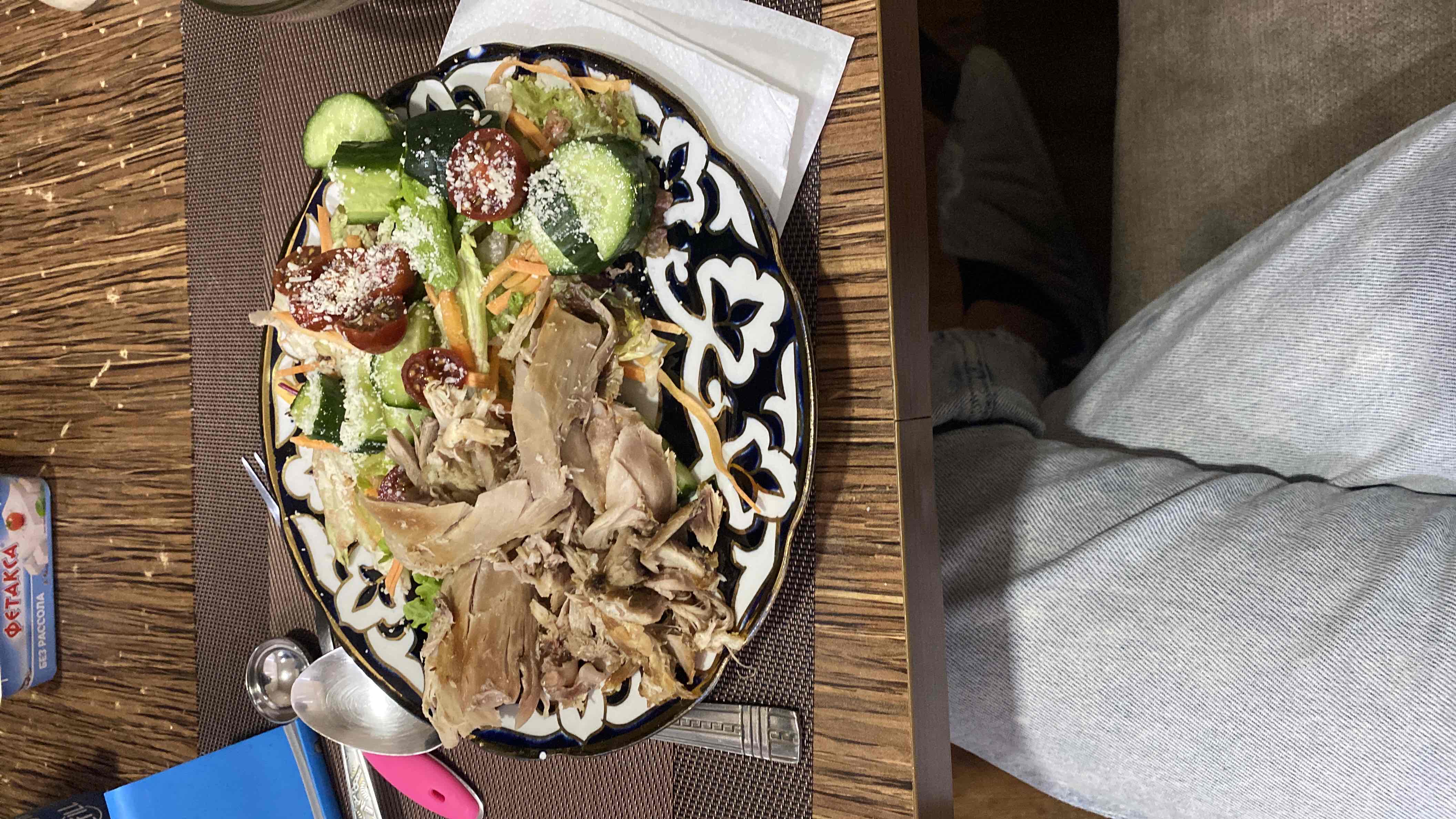 A balanced meal consisting of shredded chicken, fresh vegetables like cucumber, cherry tomatoes, lettuce, and carrots, topped with parmesan cheese.