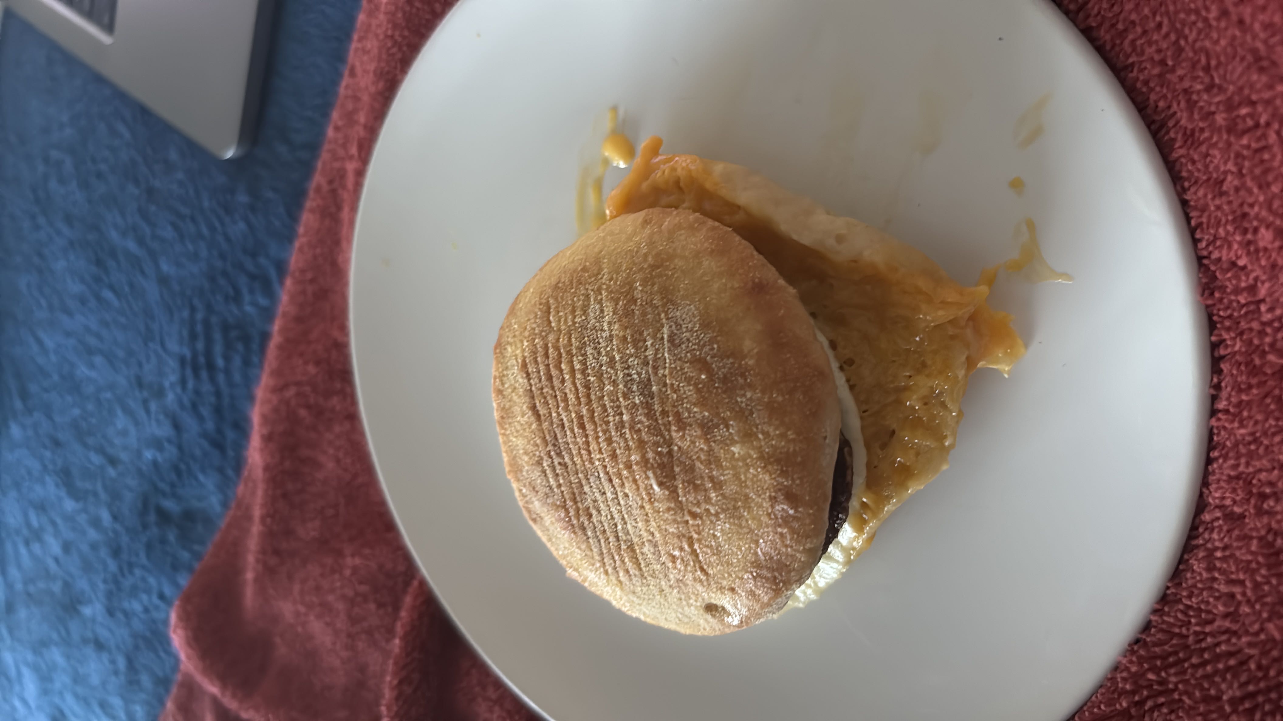 A breakfast sandwich consisting of a bread bun, cheese, egg, and butter, providing a balanced mix of protein, carbs, and fats.