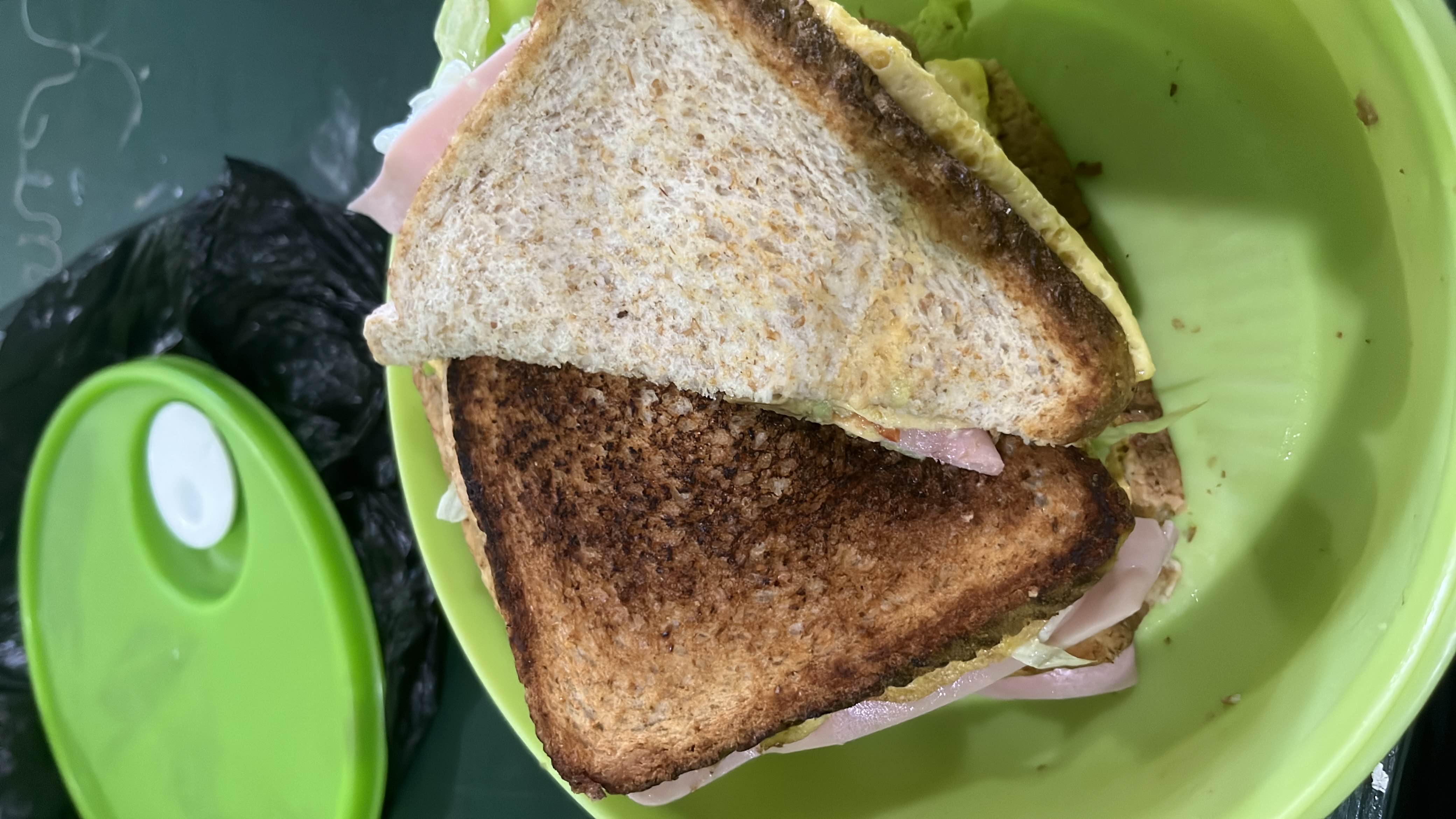 A toasted sandwich made with whole wheat bread, ham, lettuce, cheese, and egg, providing a balanced mix of protein, carbs, and fats.