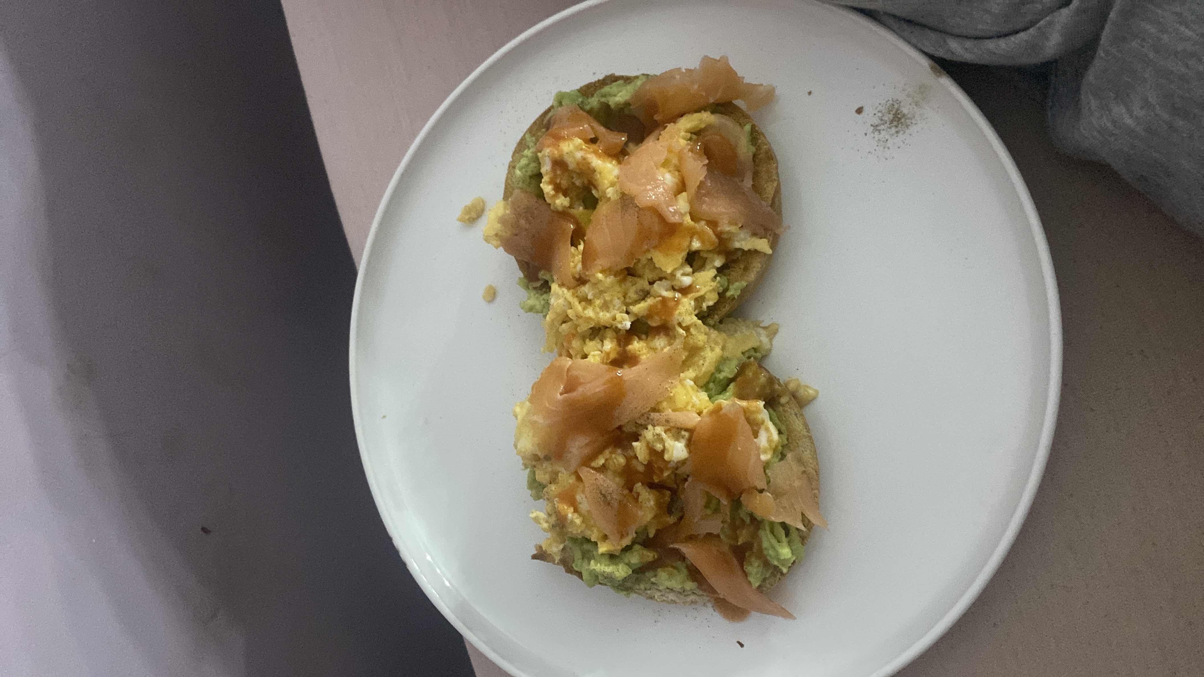 A nutritious dish featuring avocado, scrambled eggs, and smoked salmon on a toasted base, providing a balanced mix of protein, healthy fats, and carbs.