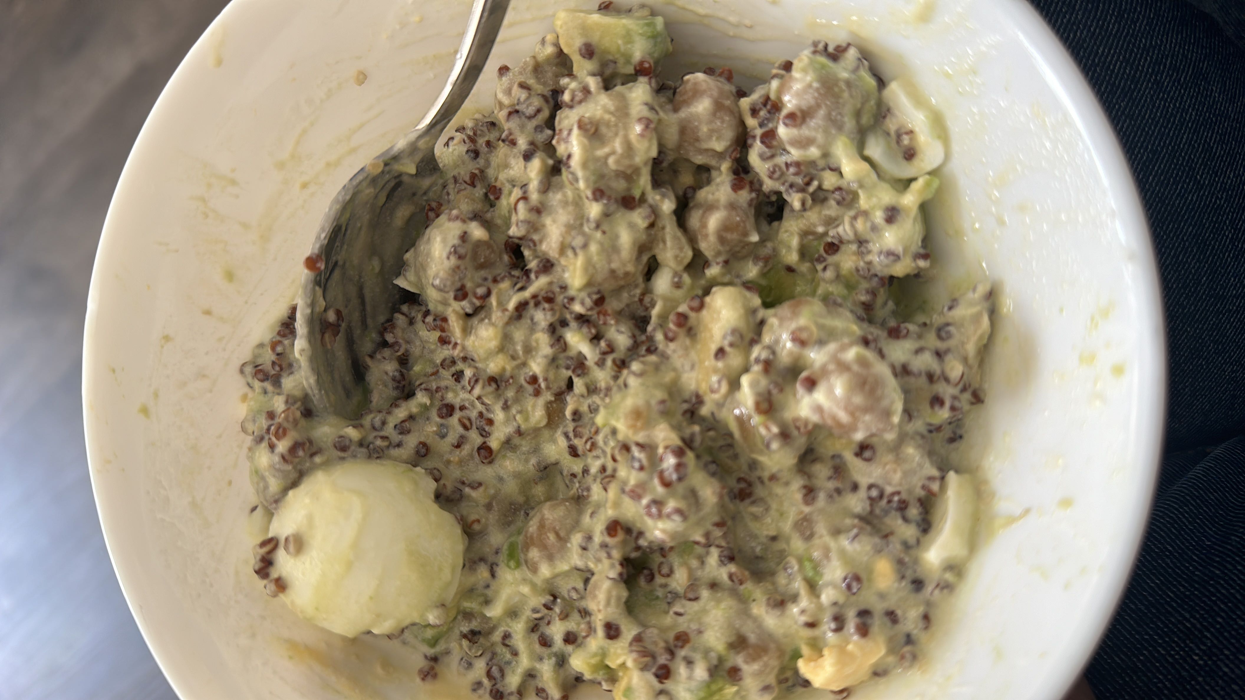 A nutritious bowl containing quinoa, avocado, boiled egg, yogurt, and walnuts, providing a balanced mix of protein, healthy fats, and carbohydrates.