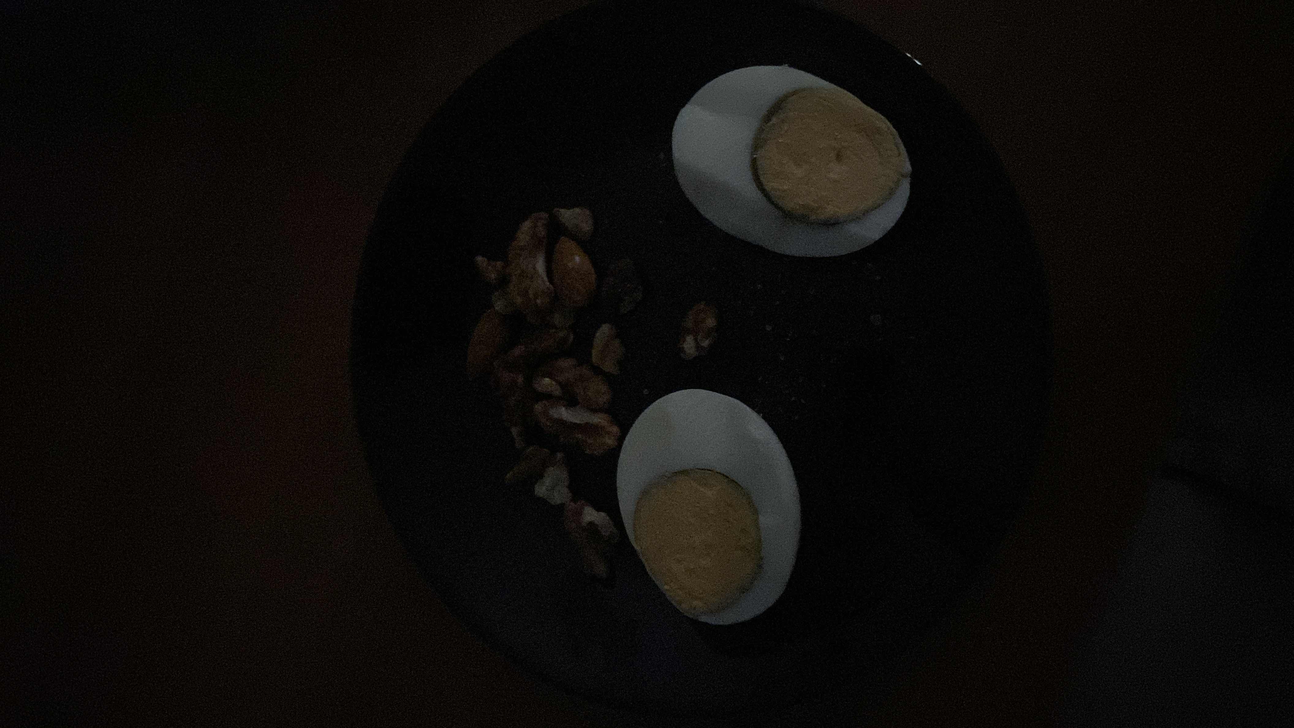 The image shows a plate with two boiled egg halves and a handful of mixed nuts, providing a high-protein and nutrient-dense snack.