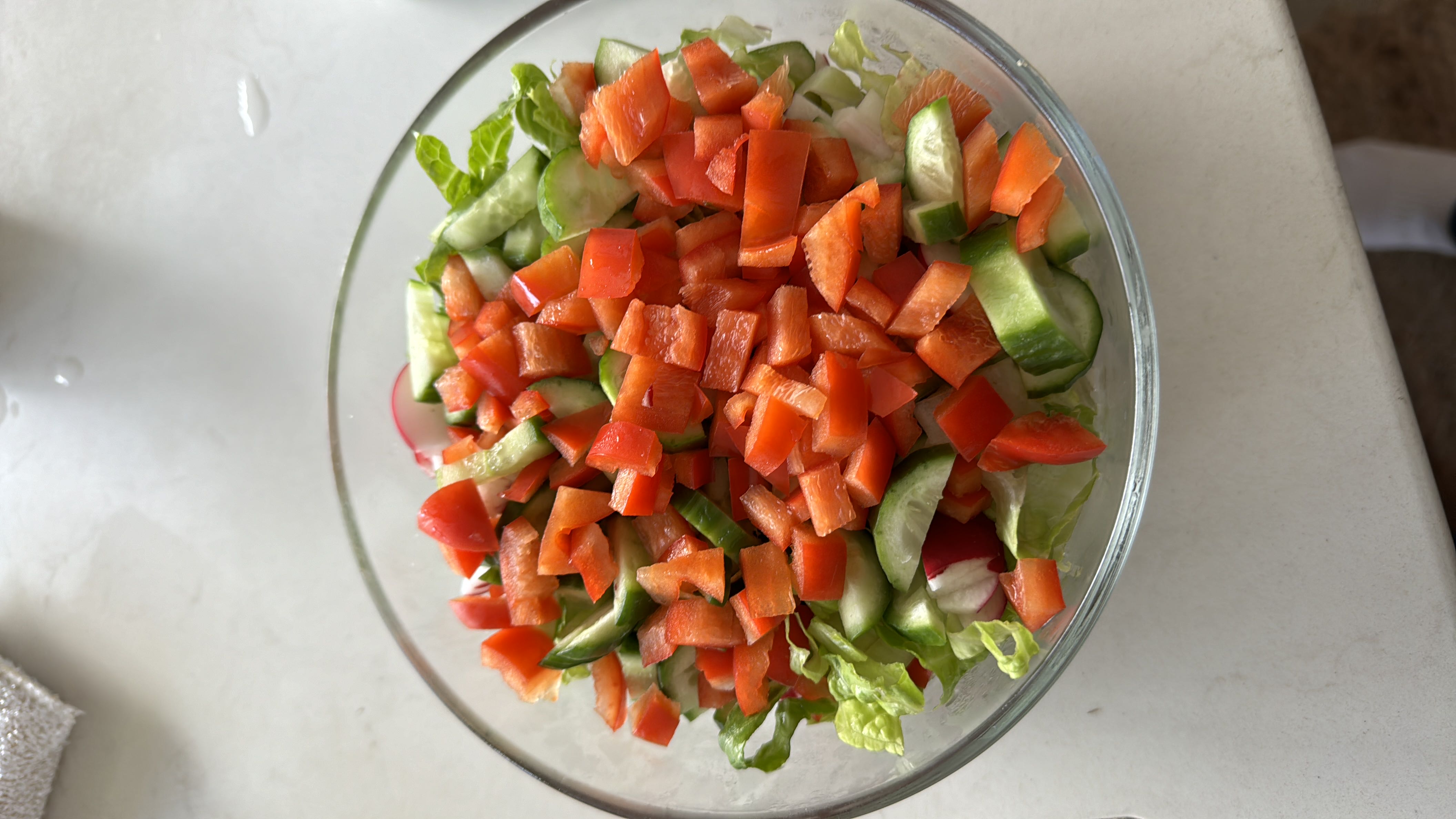 A fresh vegetable salad containing lettuce, cucumber, red bell pepper, and radish, offering a low-calorie, nutrient-rich meal.