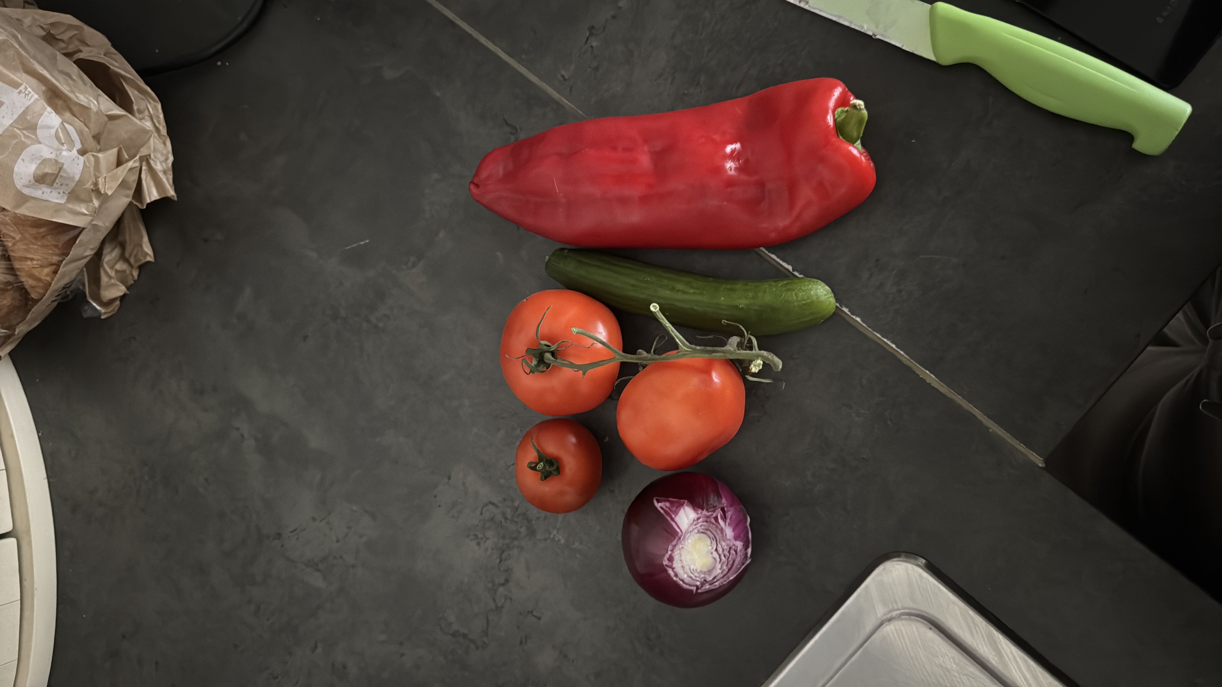 The image contains fresh vegetables including tomatoes, a red bell pepper, a cucumber, and a red onion, which are low in calories and rich in nutrients.