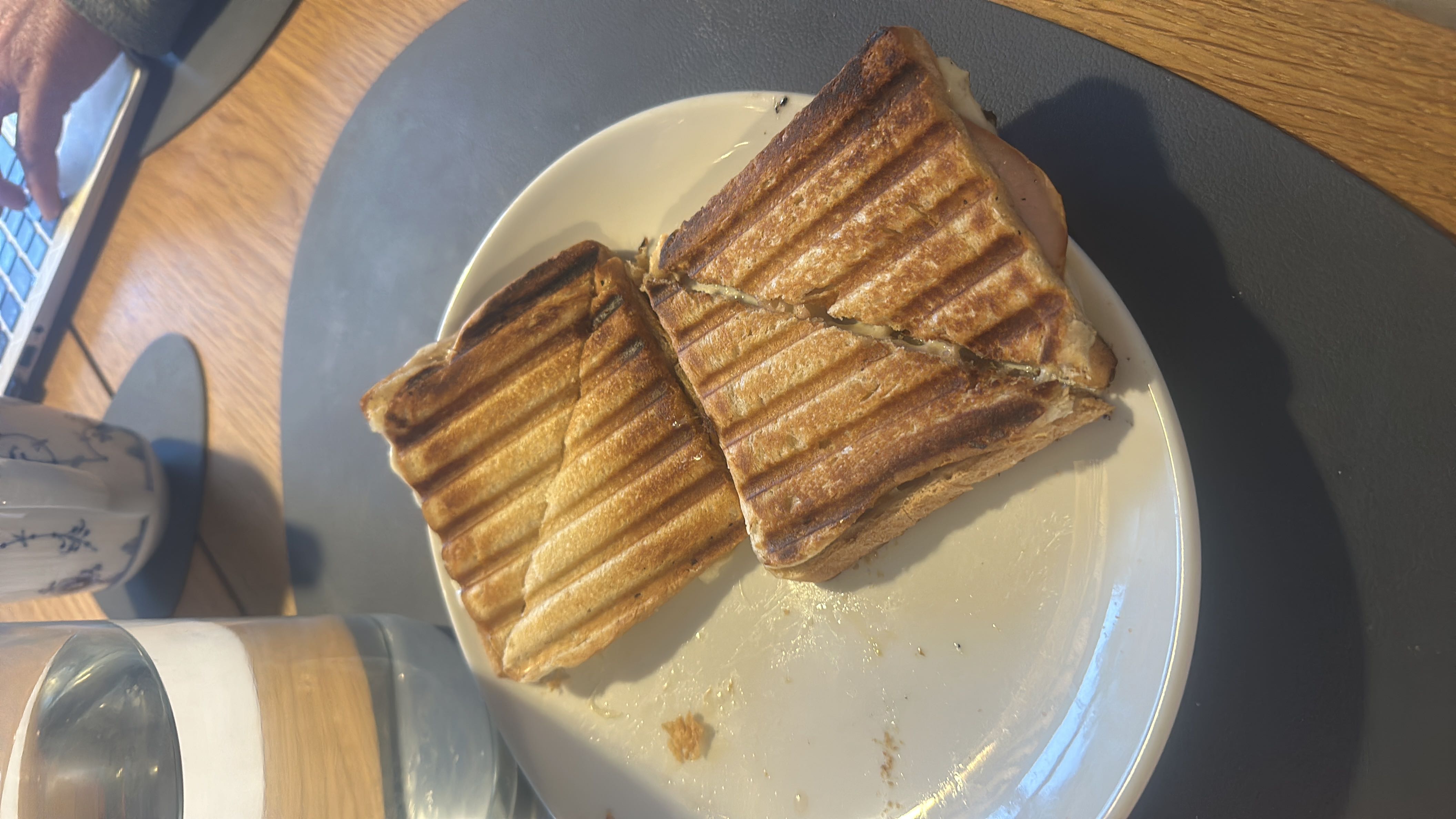 A grilled sandwich with bread, cheese, and ham, served on a plate.