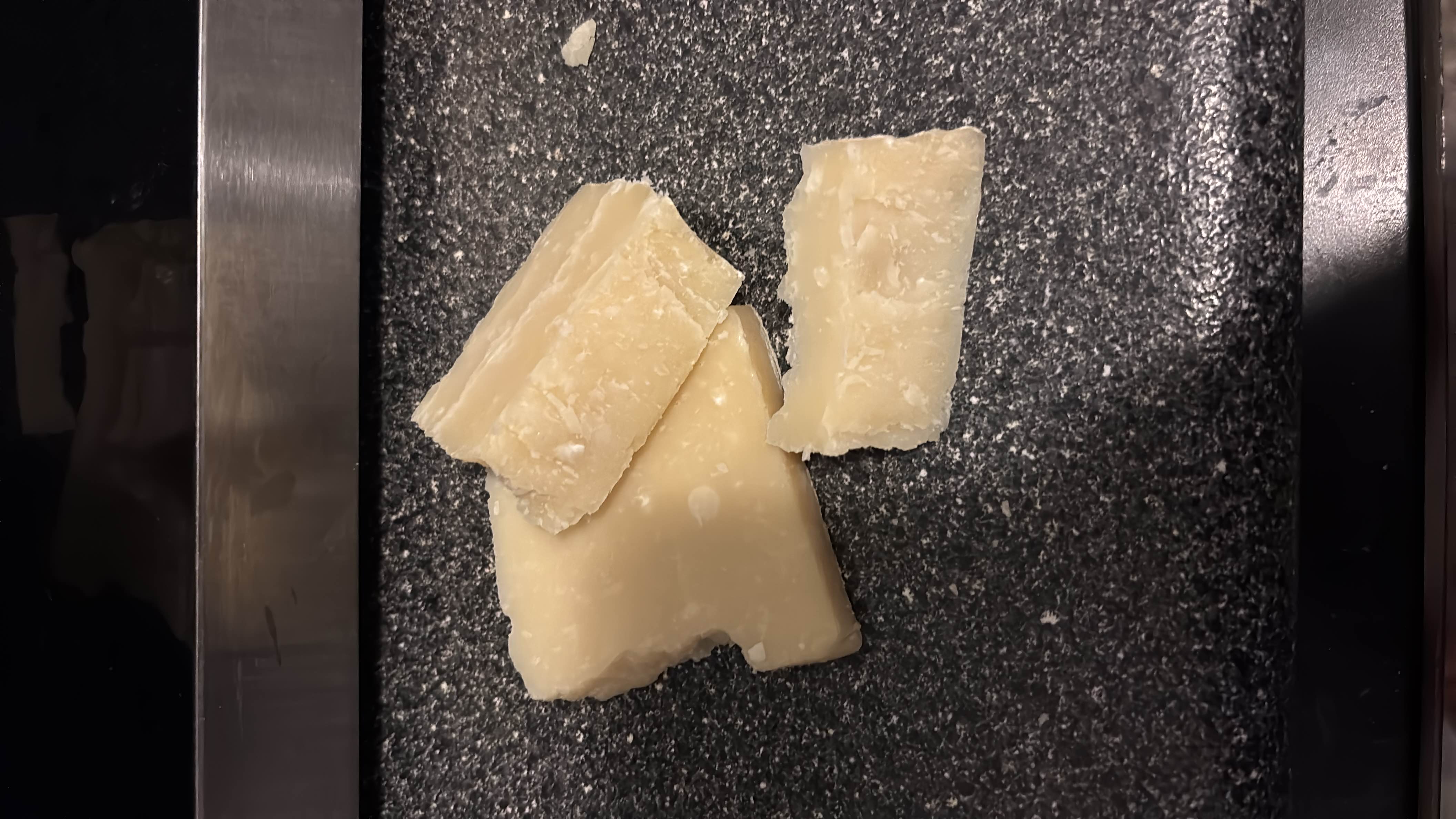 The image shows pieces of Parmesan cheese, a high-protein, low-carb dairy product with moderate fat content.
