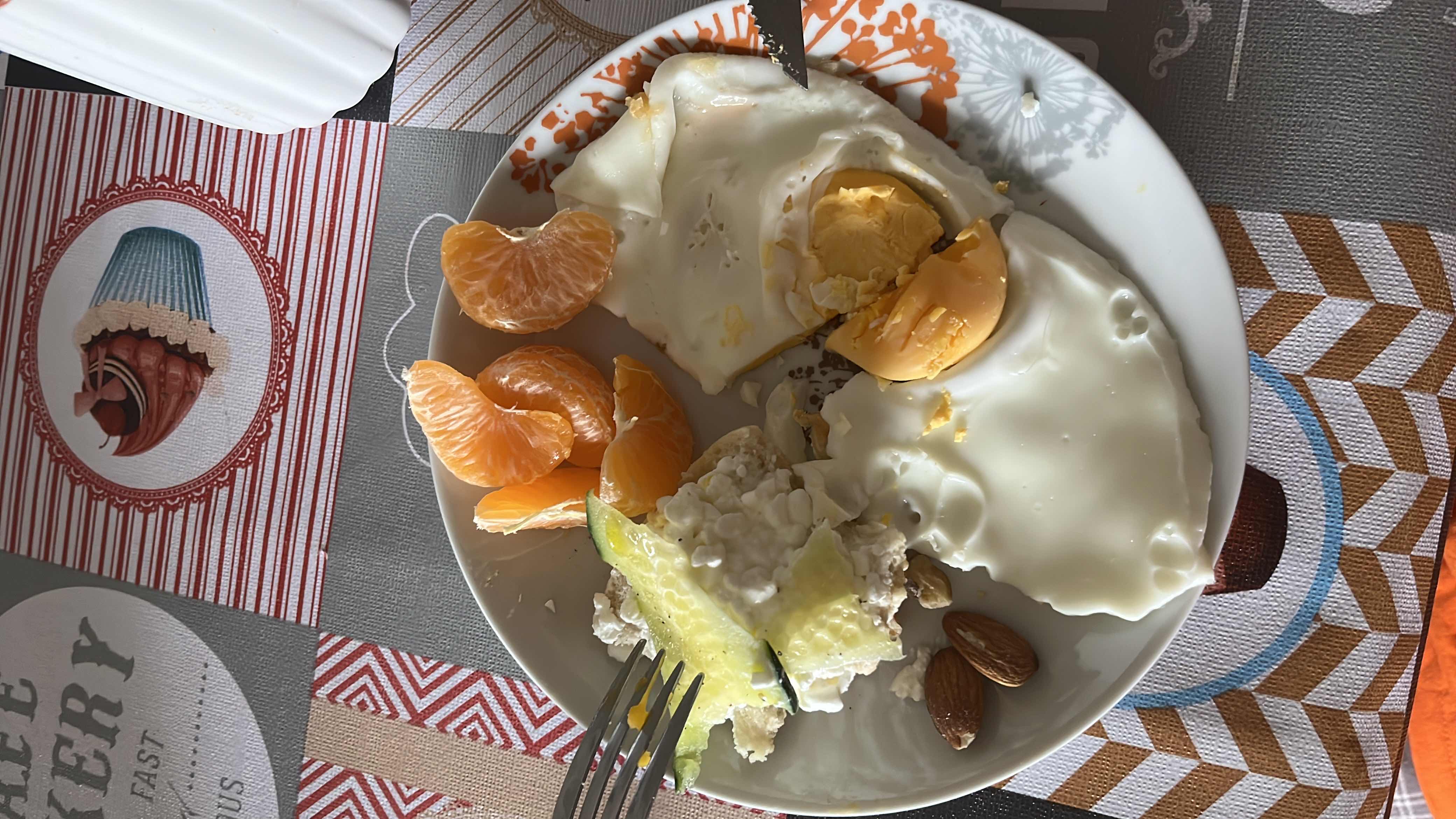 A balanced meal consisting of eggs, cottage cheese, almonds, mandarin orange slices, and cucumber, providing a good mix of protein, healthy fats, and carbohydrates.