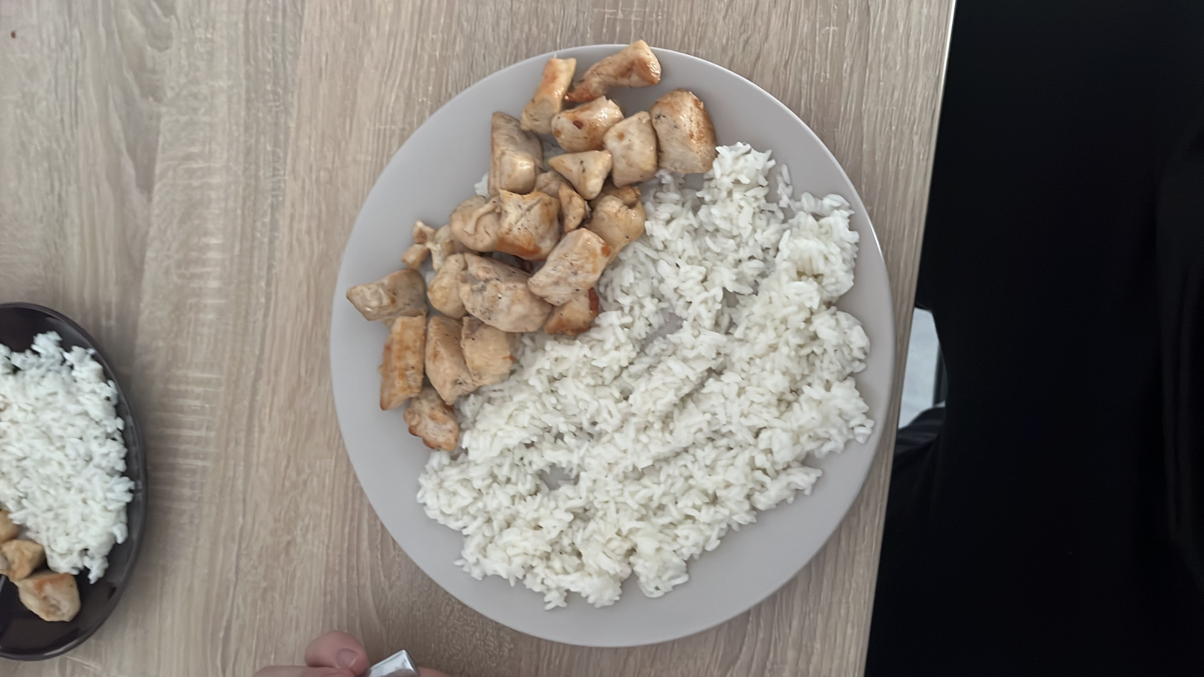 A plate of cooked white rice and grilled chicken, providing a balanced meal with high protein and moderate carbohydrates.