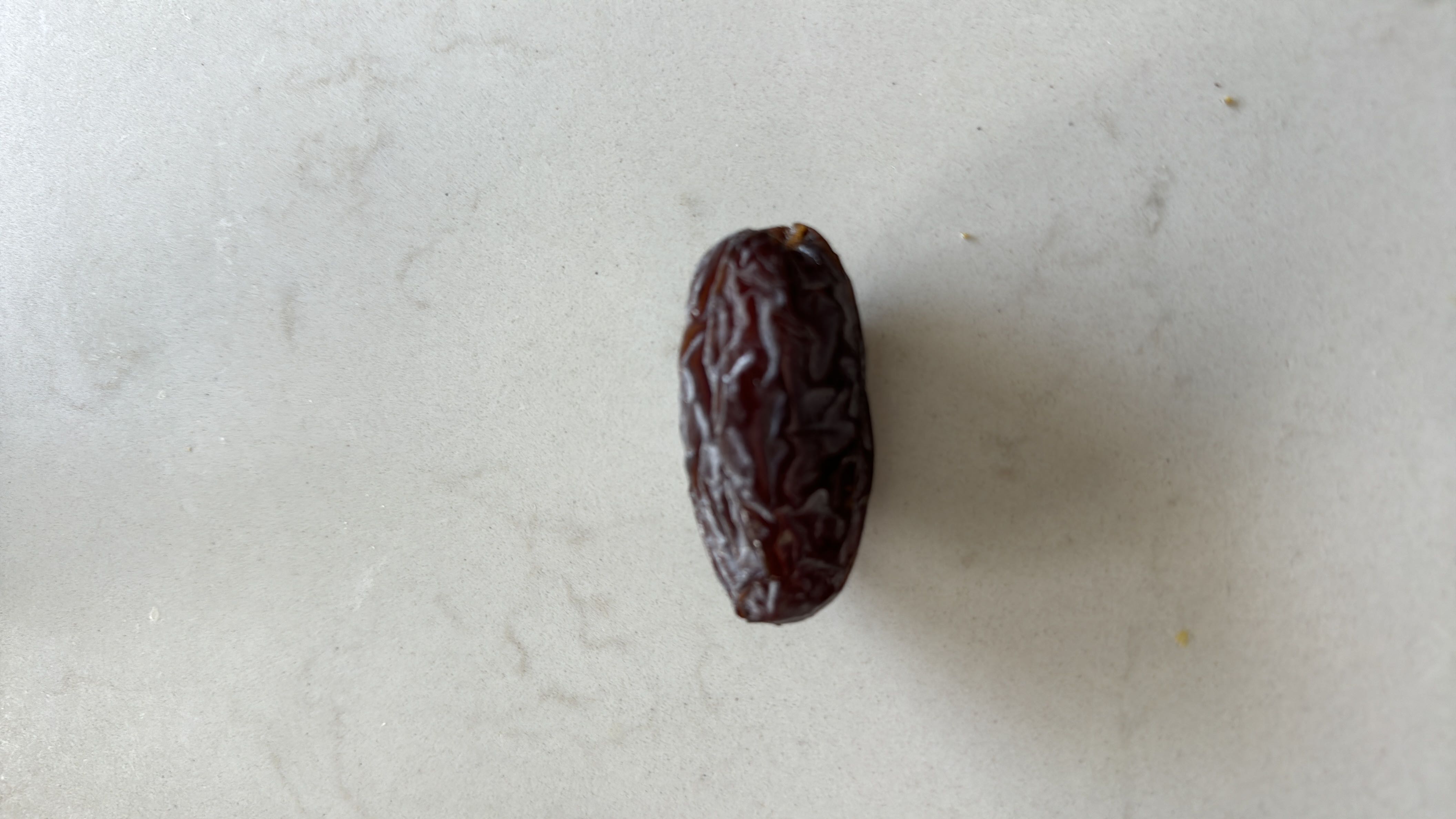 This is a single date, a nutrient-dense fruit high in natural sugars and carbohydrates, commonly used as a healthy snack or sweetener.