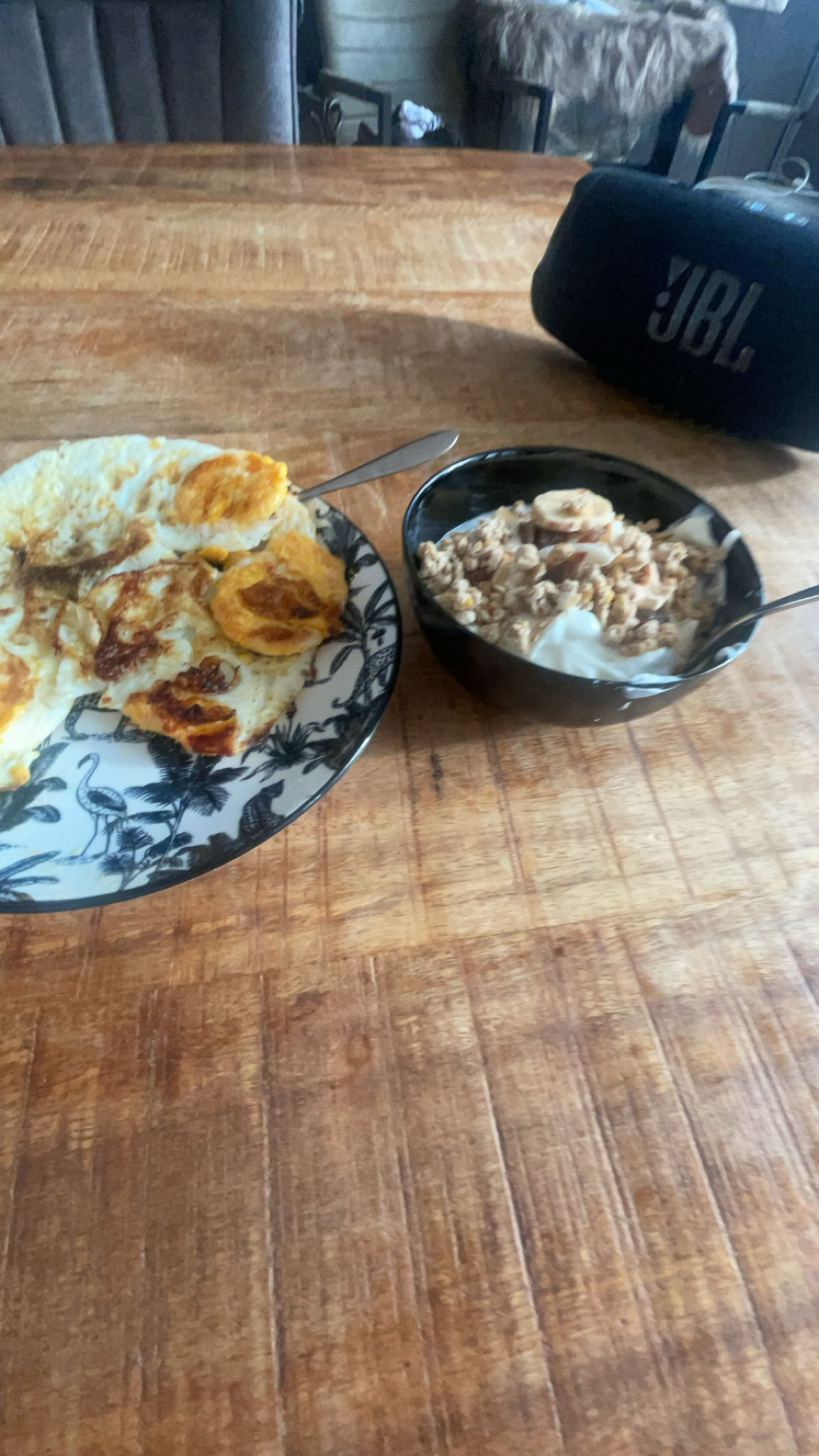 A balanced meal consisting of three fried eggs, banana slices, granola, and yogurt, providing a mix of protein, carbs, and fats.