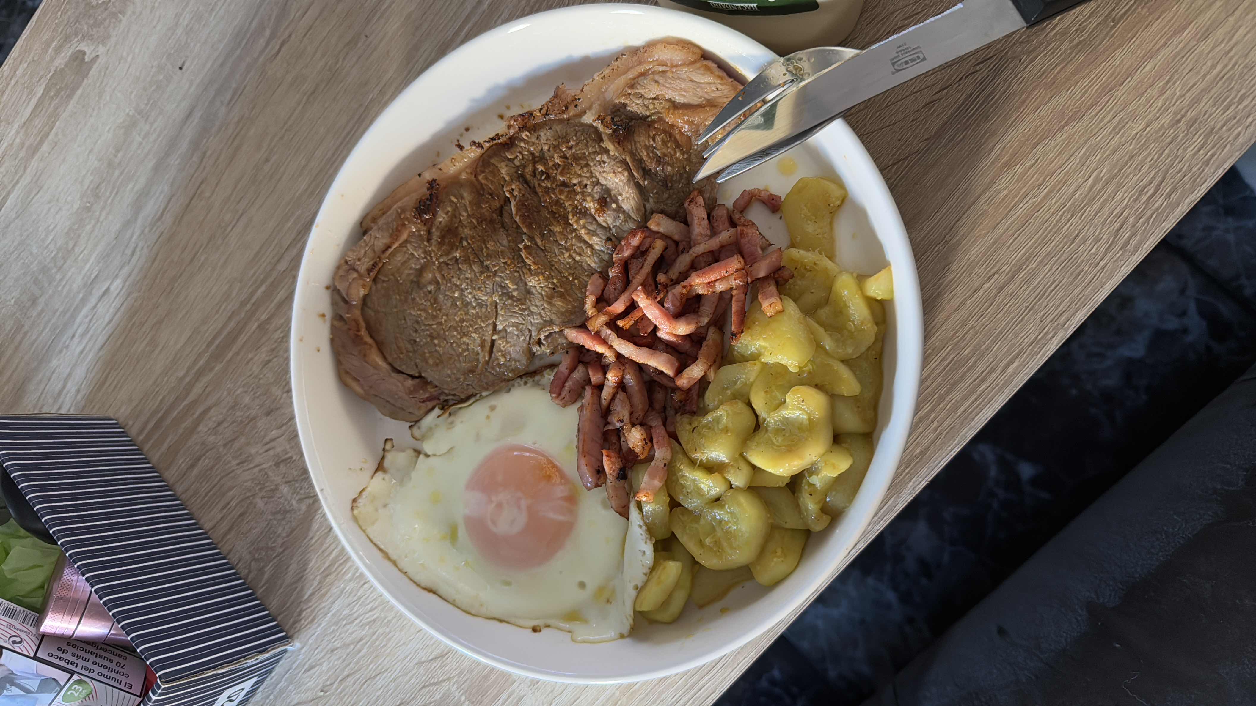 A balanced meal consisting of steak, fried egg, potatoes, and bacon strips, providing a mix of protein, carbs, and fats.