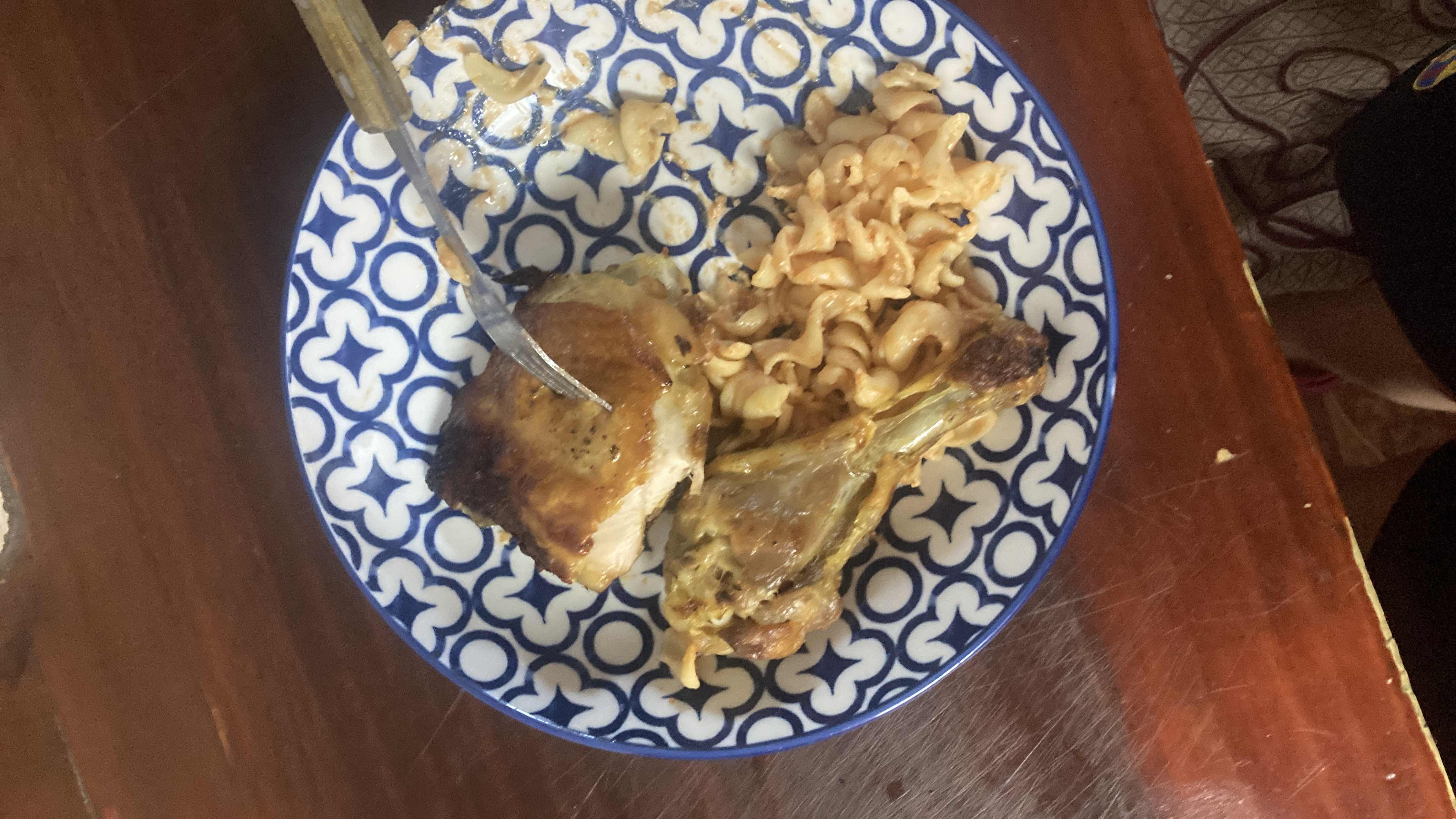 A meal consisting of roasted chicken thigh, chicken drumstick, and pasta, providing a balanced mix of protein, carbs, and fats.