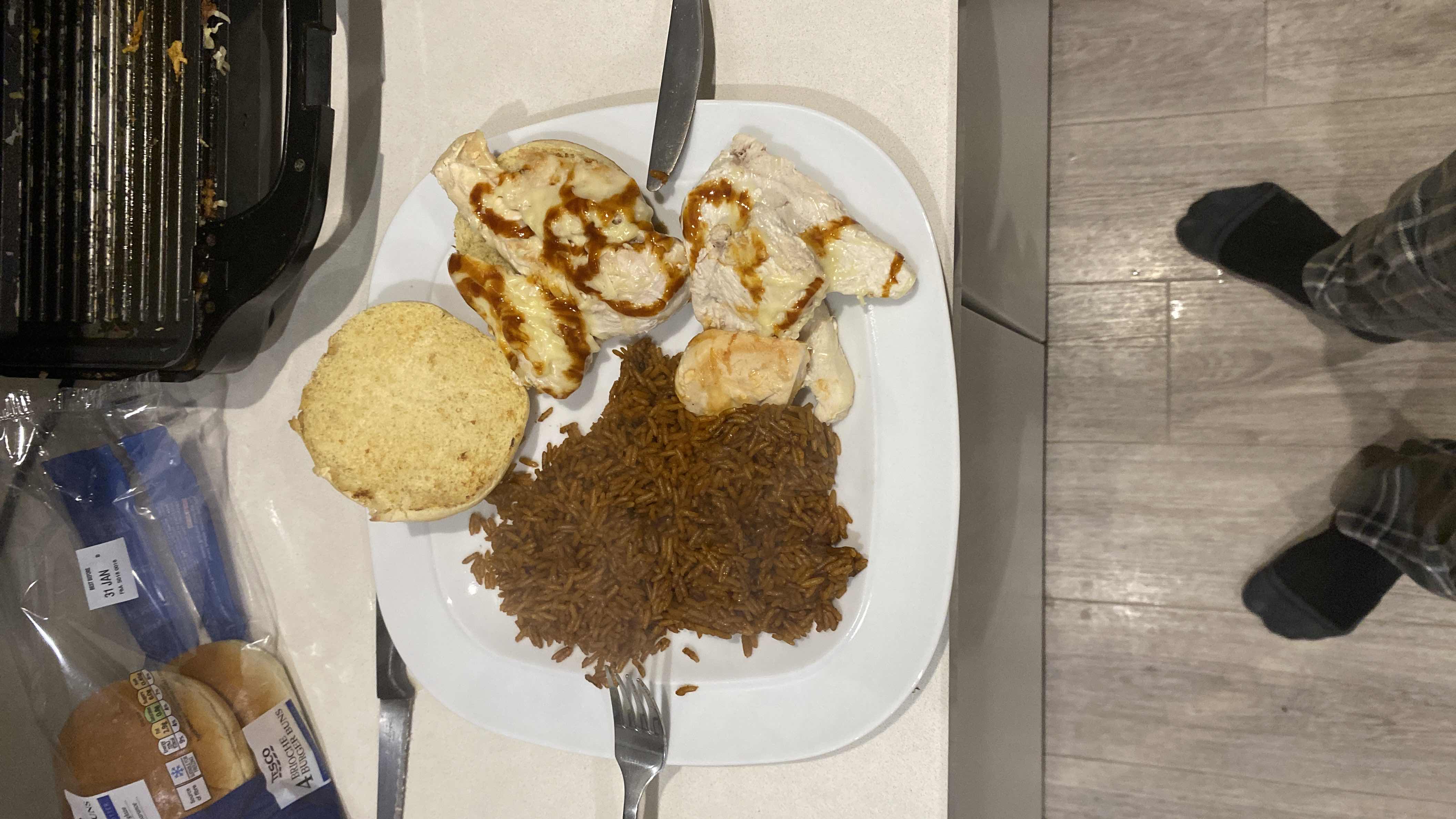 A meal consisting of grilled chicken breast, brown rice, and a burger bun, providing a balanced mix of protein, carbs, and fats.
