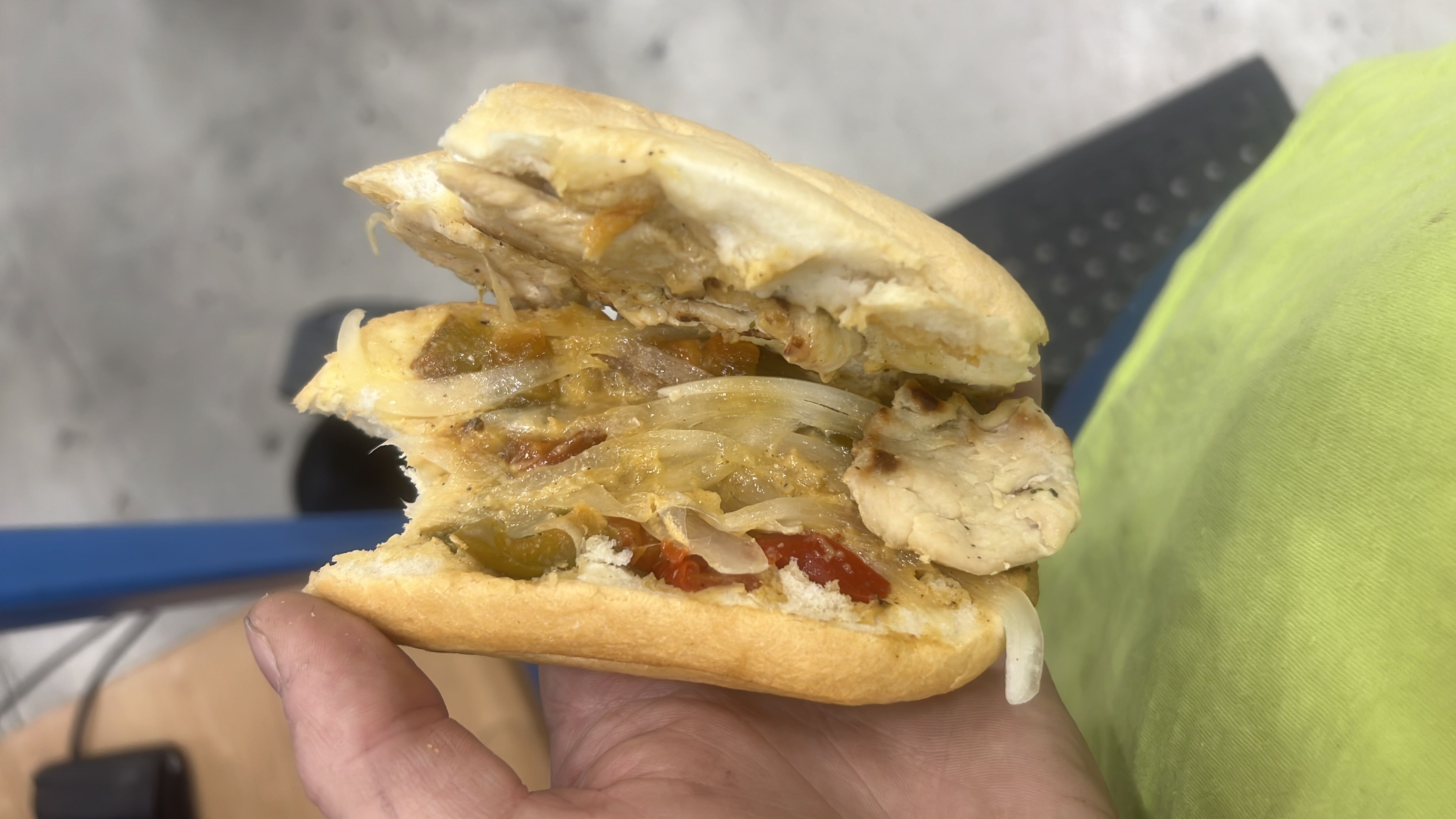 A sandwich containing chicken, bread, onions, bell peppers, and cheese, providing a balanced mix of protein, carbs, and fats.