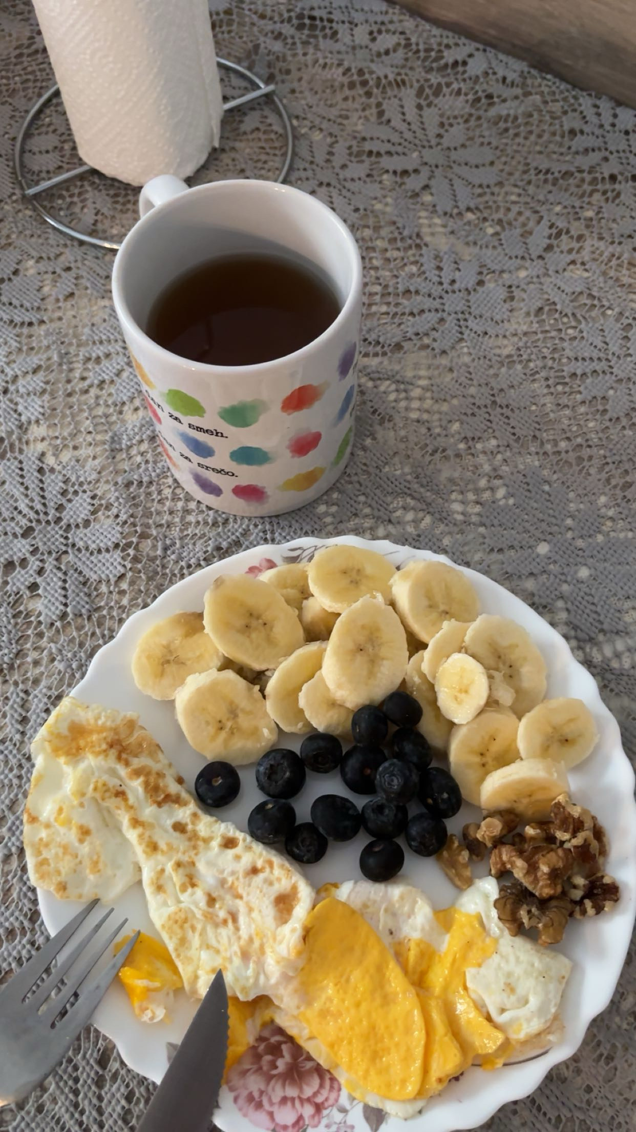 A balanced breakfast consisting of bananas, blueberries, fried eggs, walnuts, and tea, providing a mix of protein, carbs, and healthy fats.
