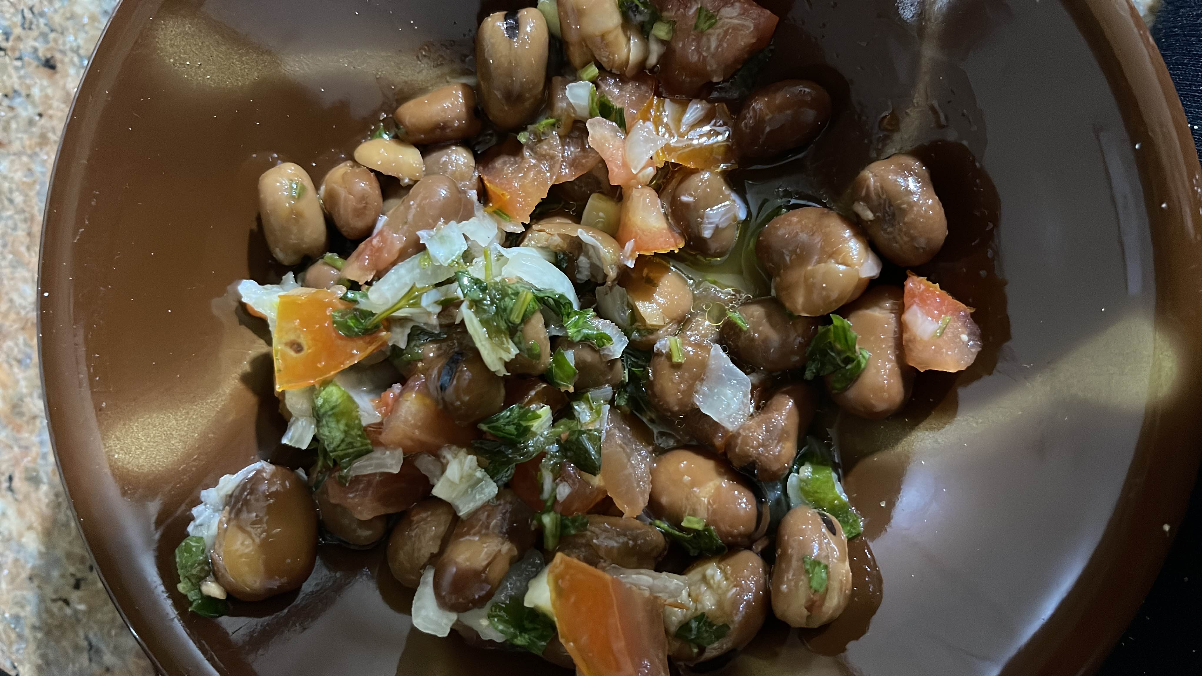 A nutritious dish featuring fava beans mixed with fresh vegetables like tomatoes, parsley, and onions, providing a balanced source of protein, carbs, and fats.