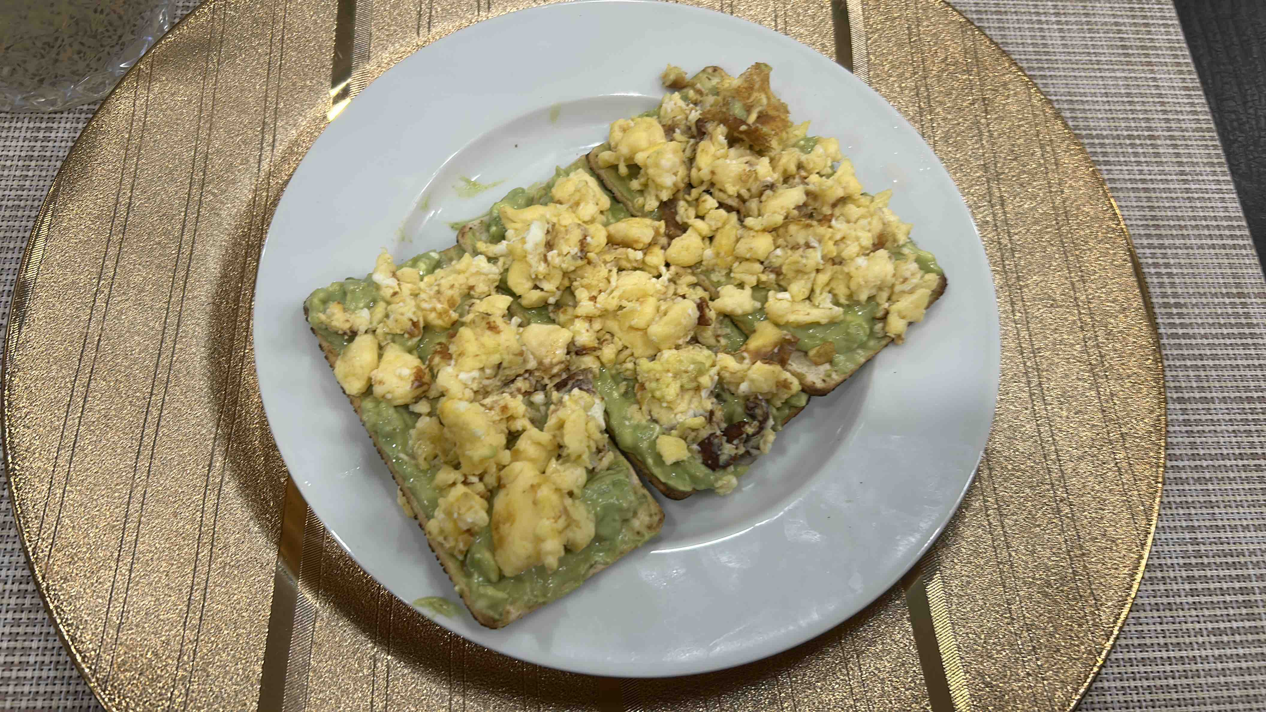 This dish consists of avocado spread on toast topped with scrambled eggs, providing a balanced mix of healthy fats, protein, and carbohydrates.