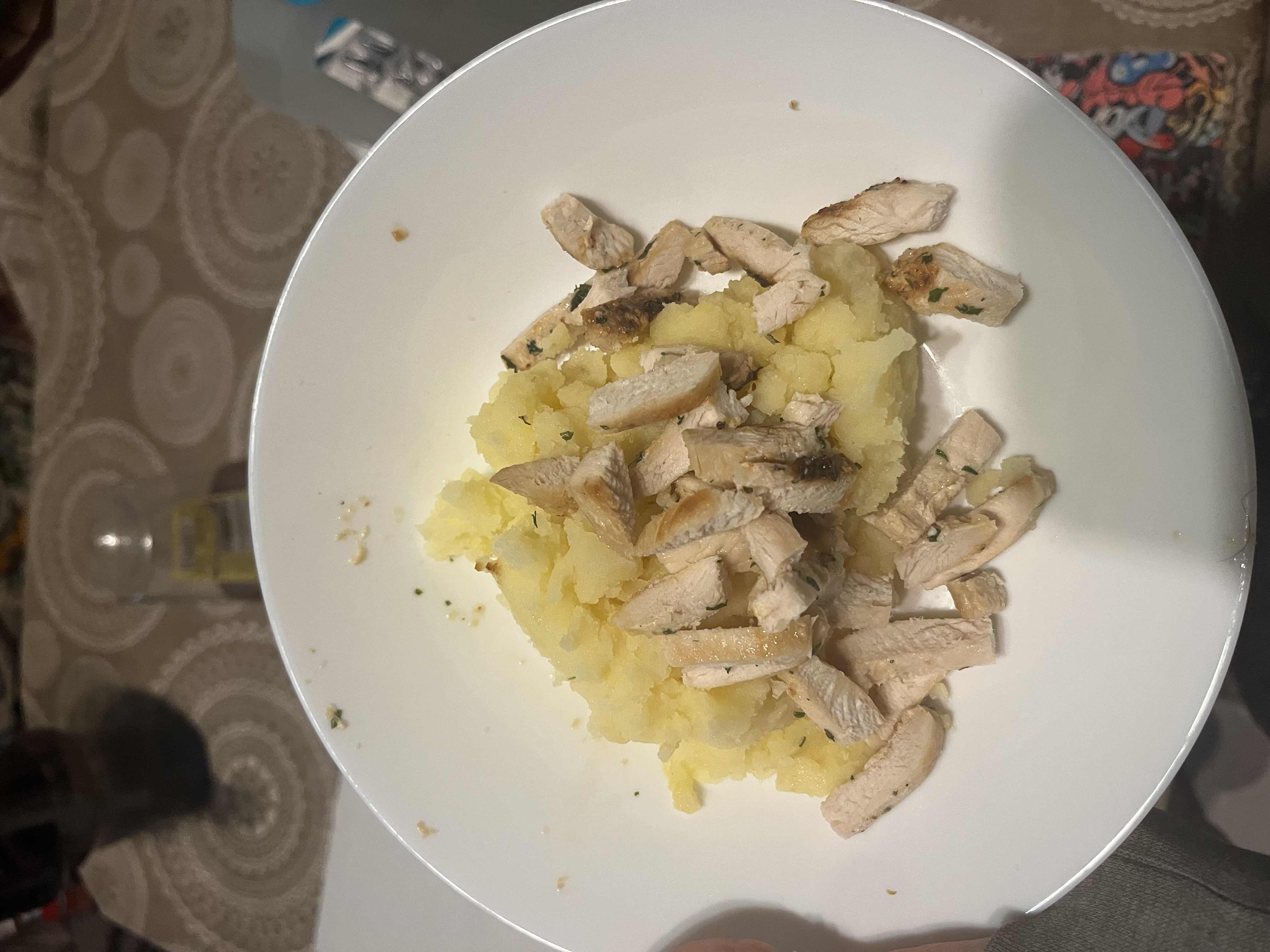 A dish consisting of grilled chicken breast pieces served over mashed potatoes, providing a balanced mix of protein and carbohydrates.