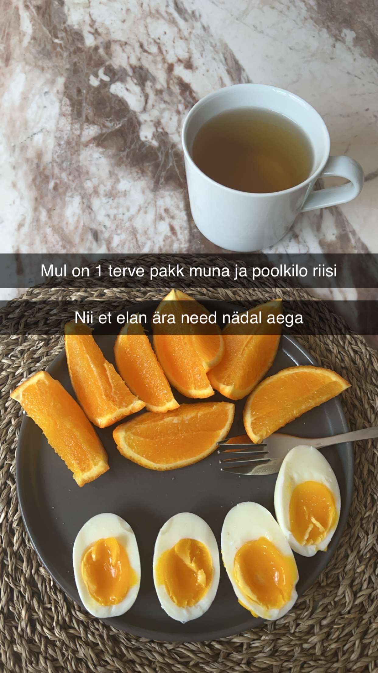 A simple meal consisting of boiled eggs, orange slices, and a cup of tea, providing a balanced mix of protein, carbs, and fats.