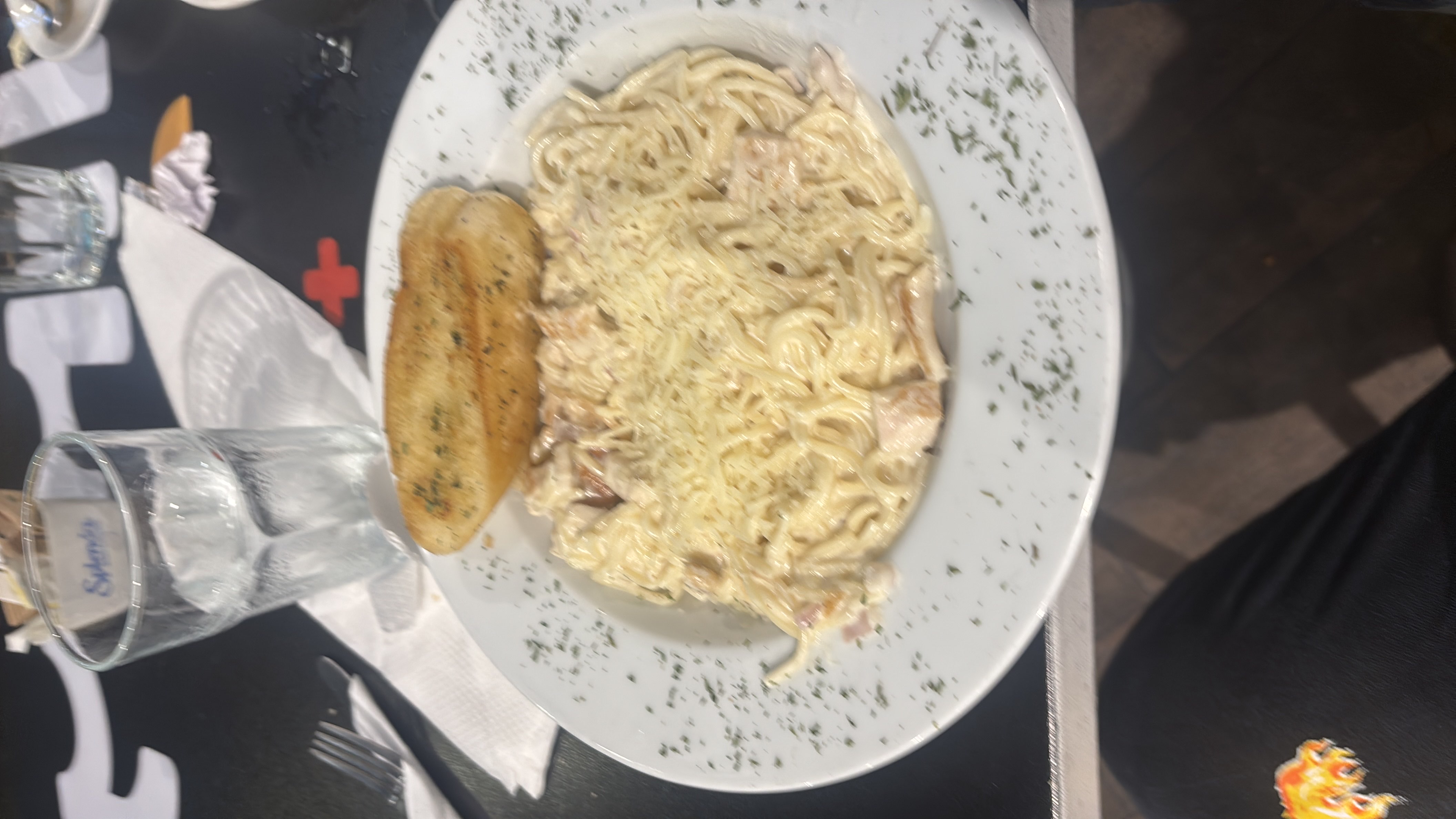 A plate of creamy chicken spaghetti served with garlic bread, garnished with herbs.