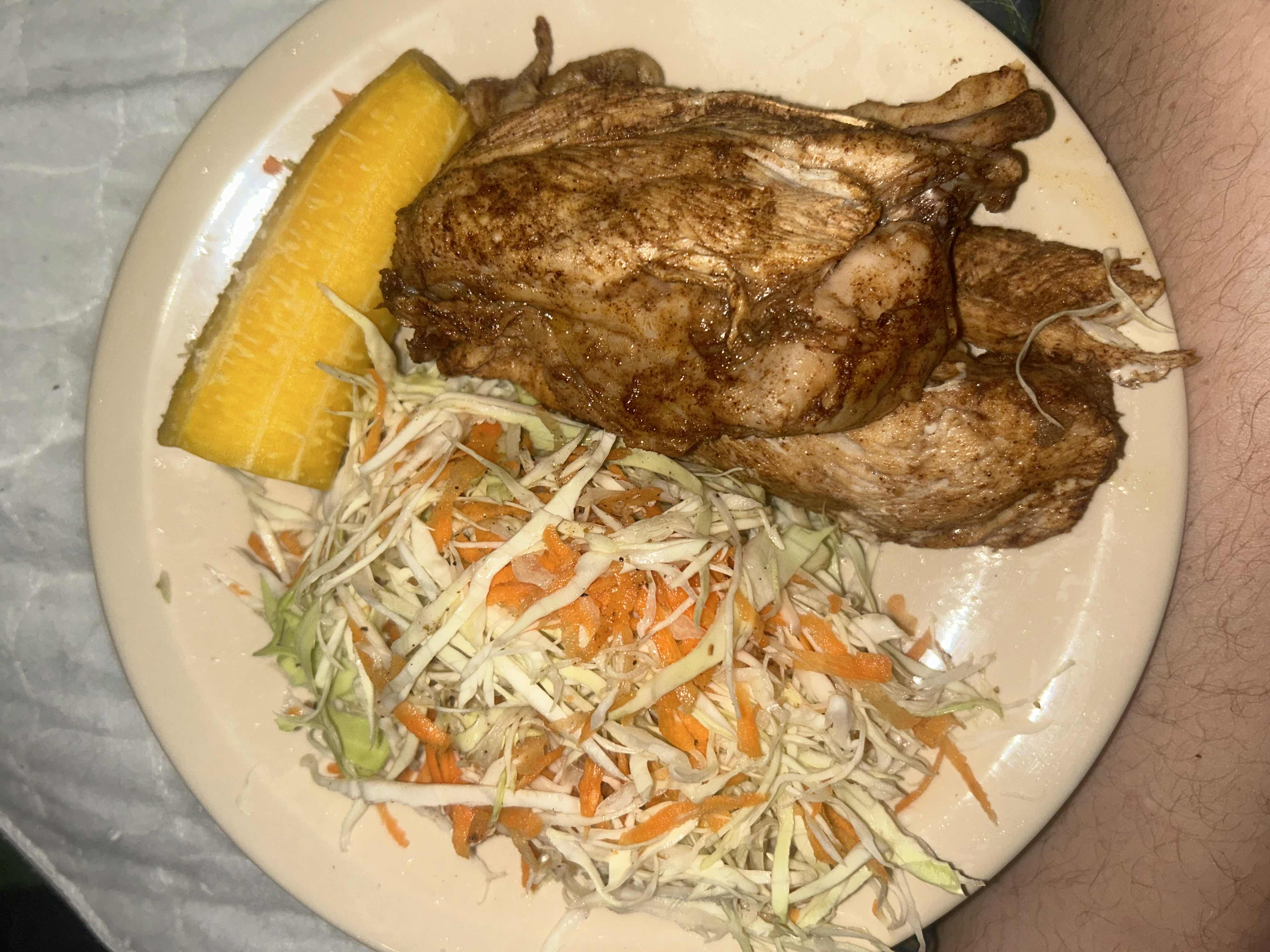 A balanced meal consisting of seasoned chicken, a fresh cabbage and carrot salad, and a portion of boiled plantain.