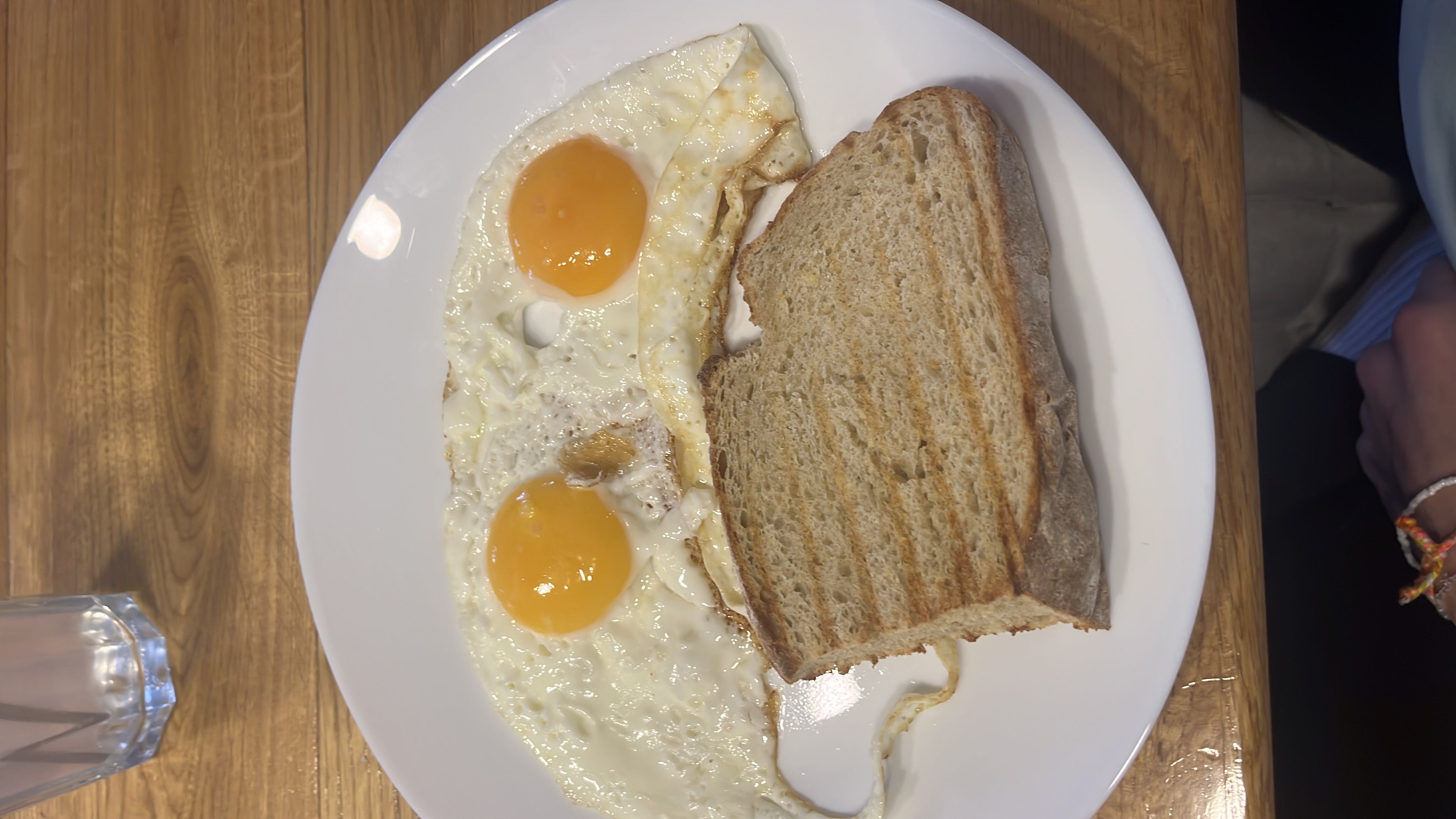 A plate containing two fried eggs and a slice of toasted bread, providing a balanced mix of protein, carbs, and fats.