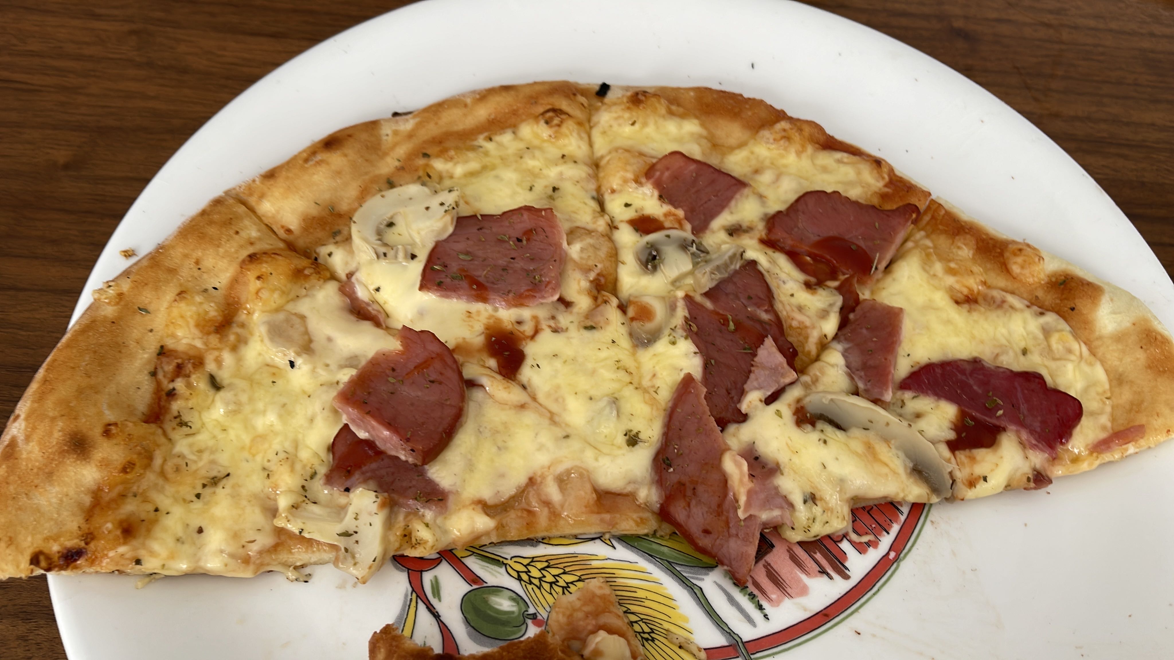 A slice of pizza topped with cheese, ham, and mushrooms, providing a balanced mix of protein, carbs, and fats.