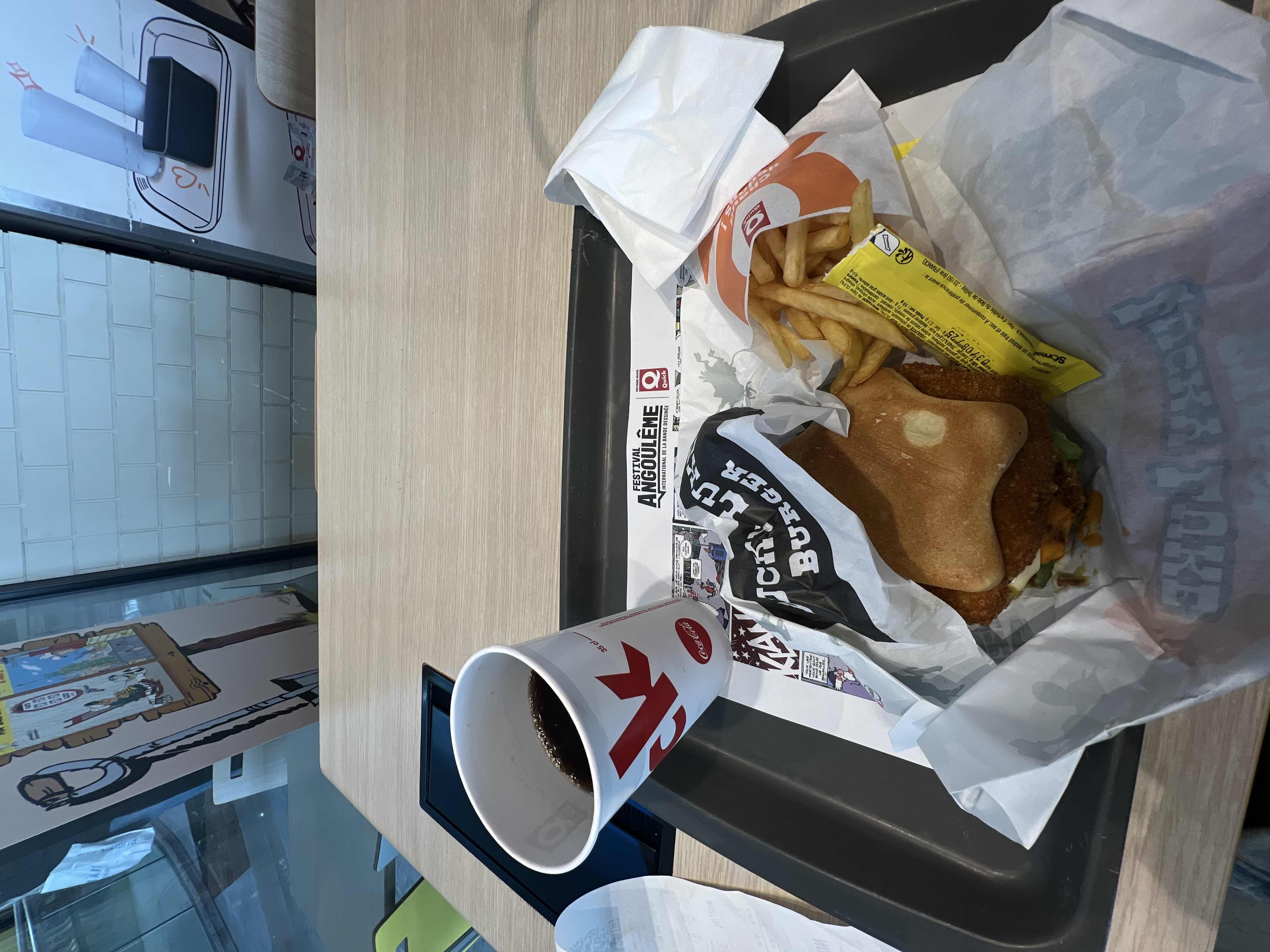 A fast food meal consisting of a chicken burger, fries, and a soda.