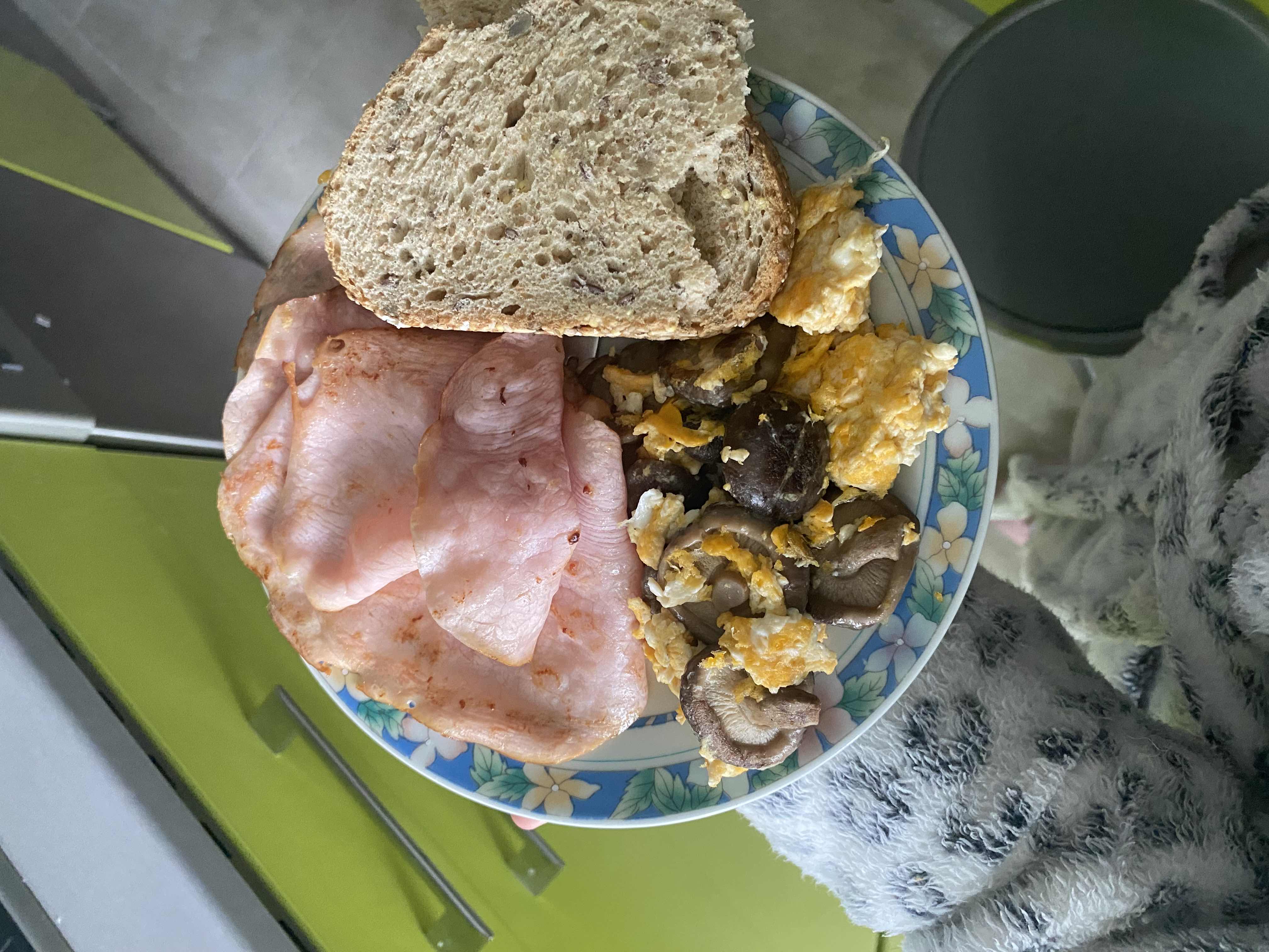 A balanced meal consisting of turkey slices, scrambled eggs with mushrooms, and whole grain bread, providing a good mix of protein, carbs, and fats.