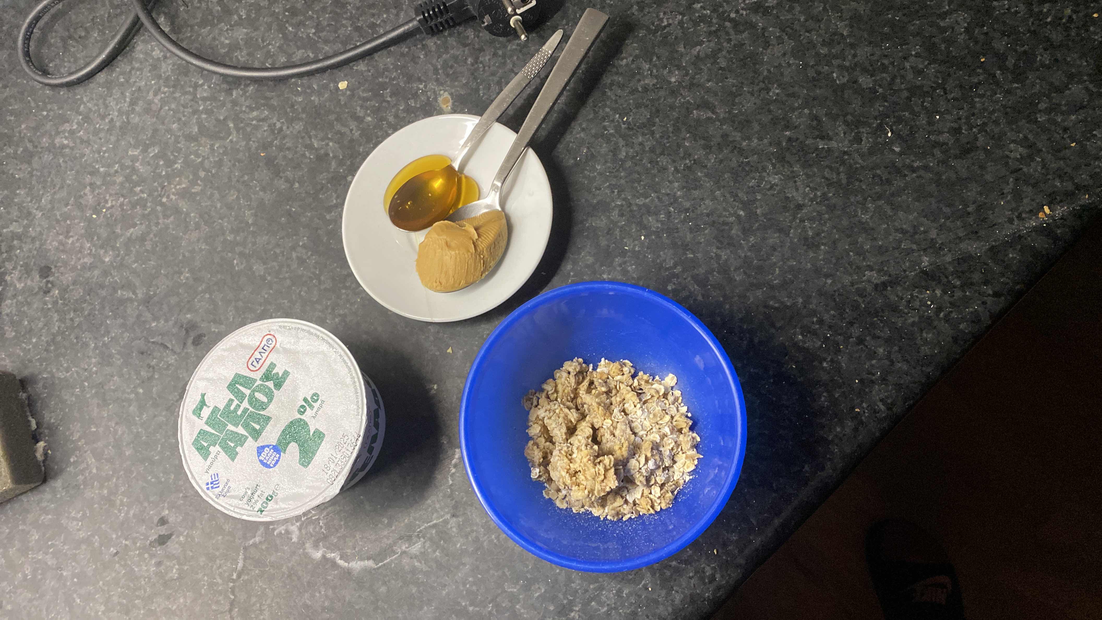 A nutritious meal consisting of Greek yogurt, granola, peanut butter, and honey, providing a balanced mix of protein, carbs, and fats.