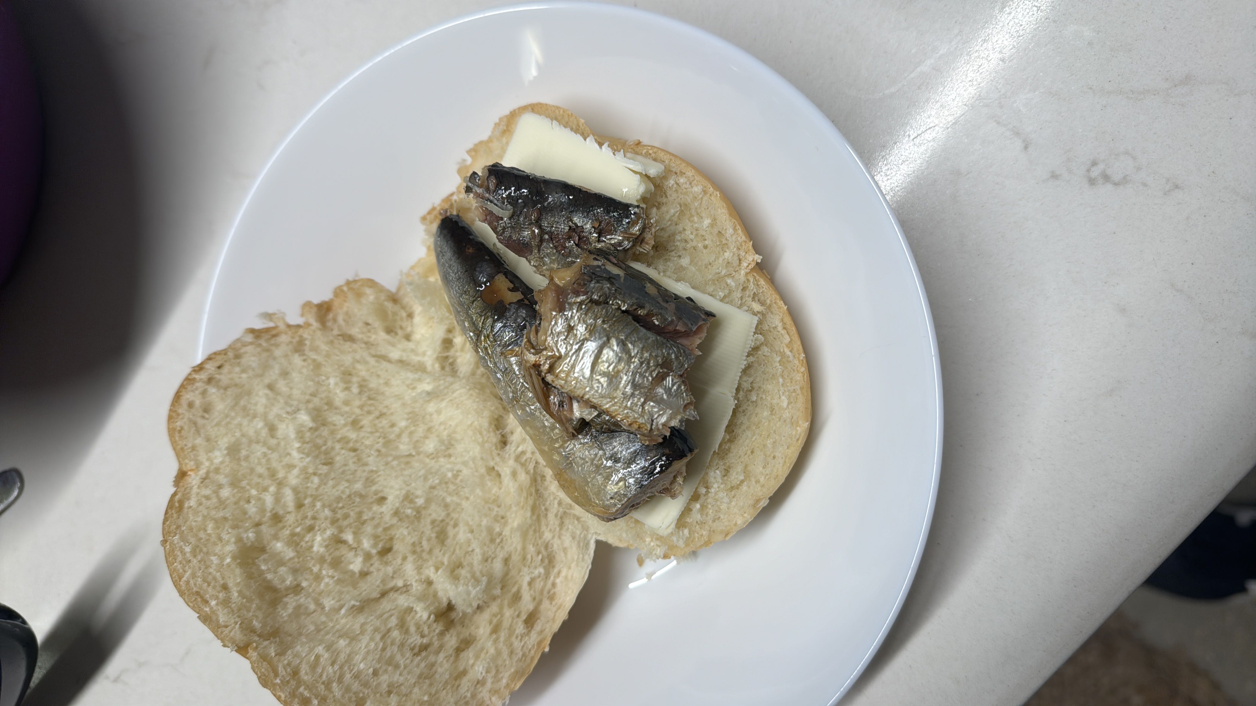 A sandwich made with bread, sardines, and cheese, providing a balanced mix of protein, carbs, and fats.