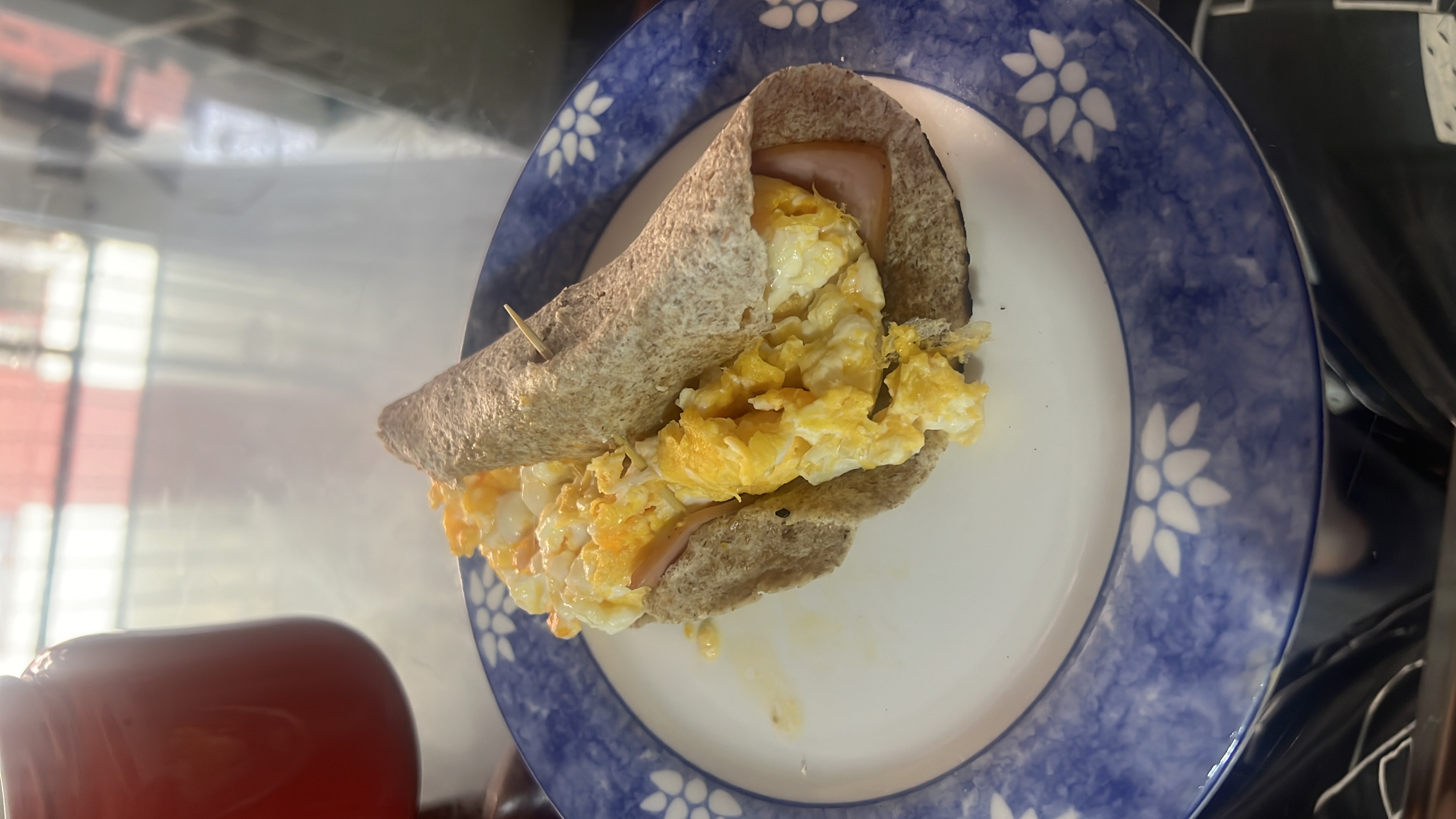 A healthy breakfast wrap made with scrambled eggs, a whole wheat tortilla, and a slice of ham.