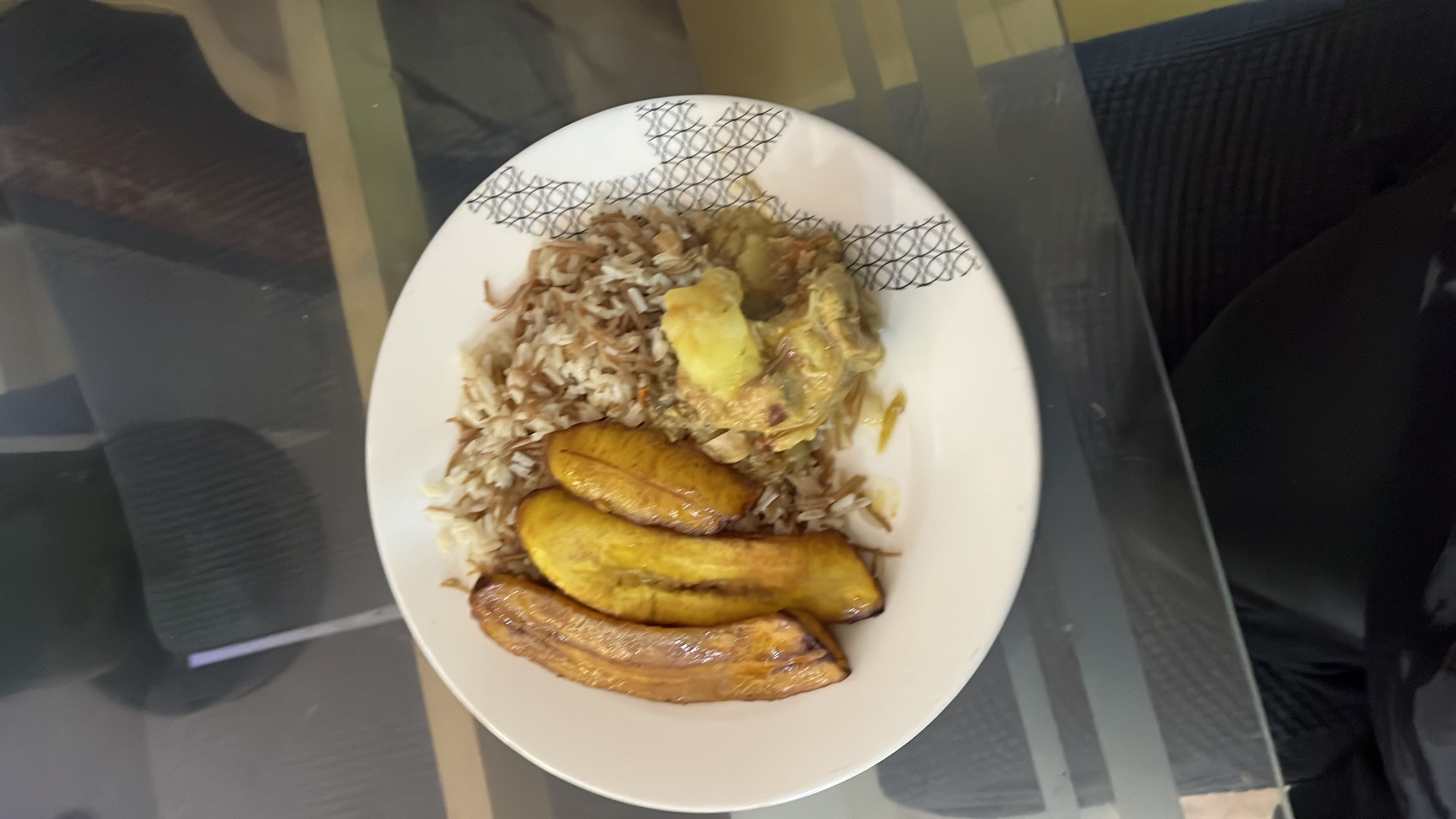 A plate of rice with fried plantains and chicken stew, providing a balanced mix of carbohydrates, protein, and fats.