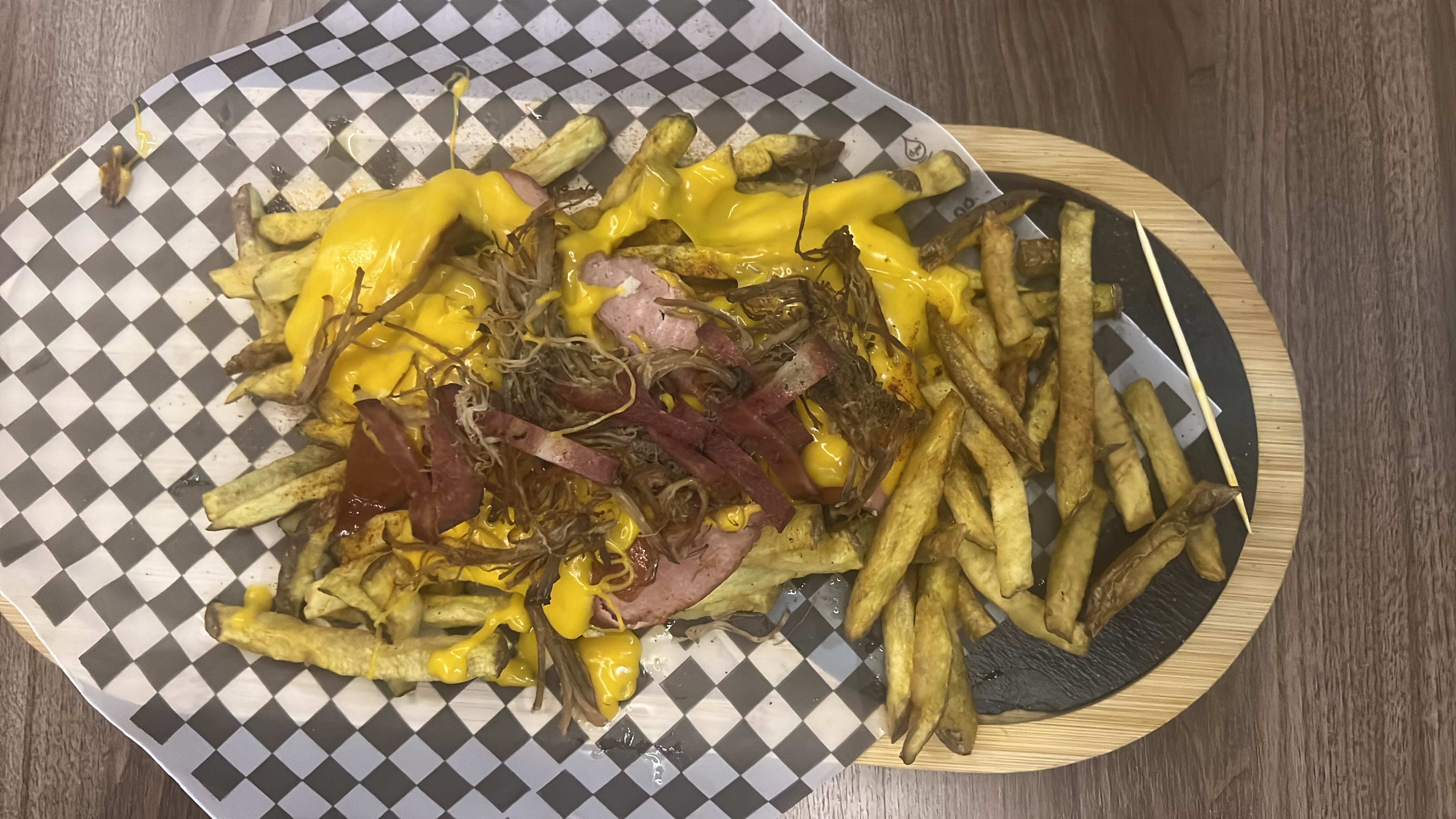 A dish consisting of French fries topped with cheese sauce, bacon strips, and fried onions, offering a high-calorie, indulgent snack.