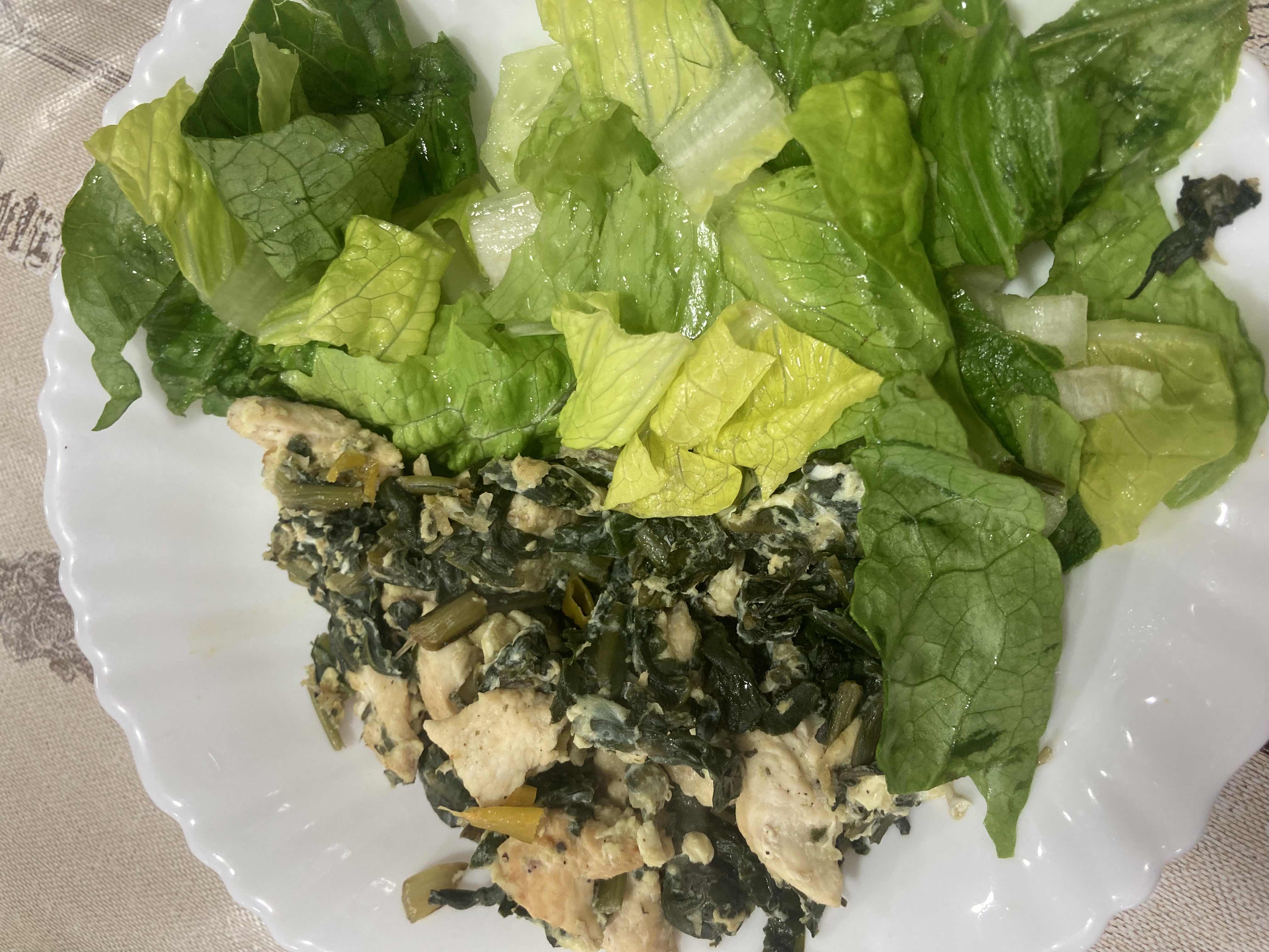 A healthy dish consisting of chicken breast, sautéed spinach, and fresh lettuce, providing a balanced mix of protein, carbs, and fats.