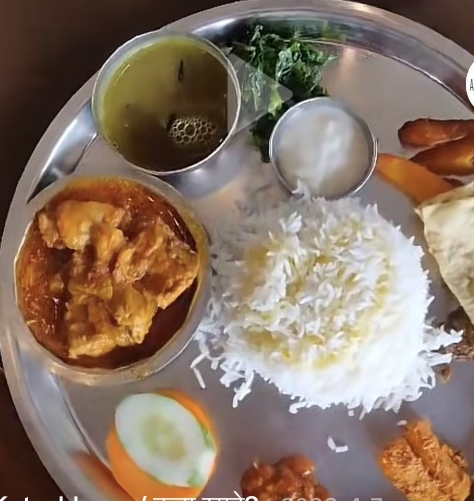 A traditional meal consisting of rice, chicken curry, lentil soup, fried fish, and vegetables, providing a balanced mix of protein, carbs, and fats.