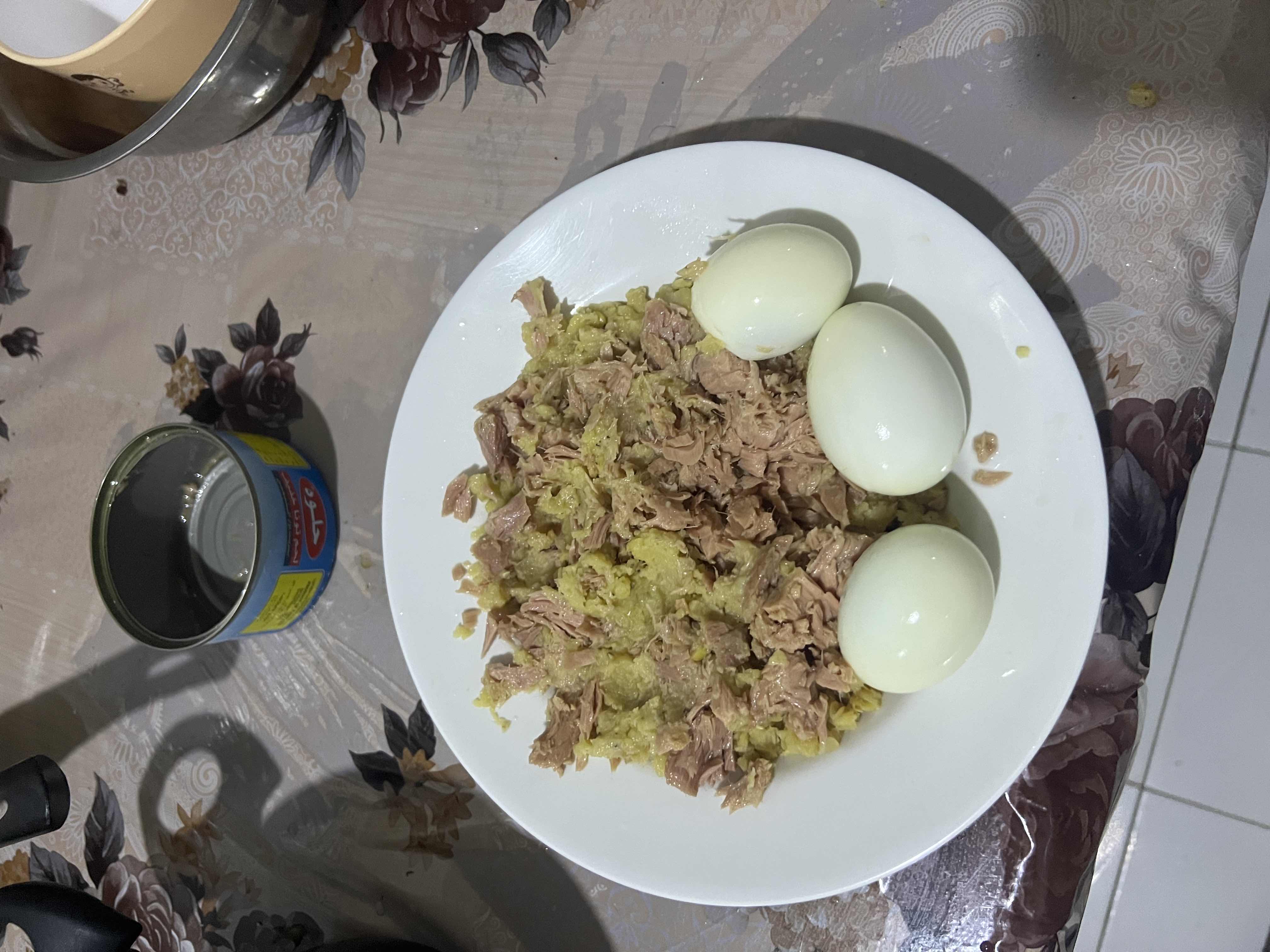 A plate containing boiled eggs, canned tuna, and mashed potatoes, providing a balanced mix of protein, carbs, and fats.