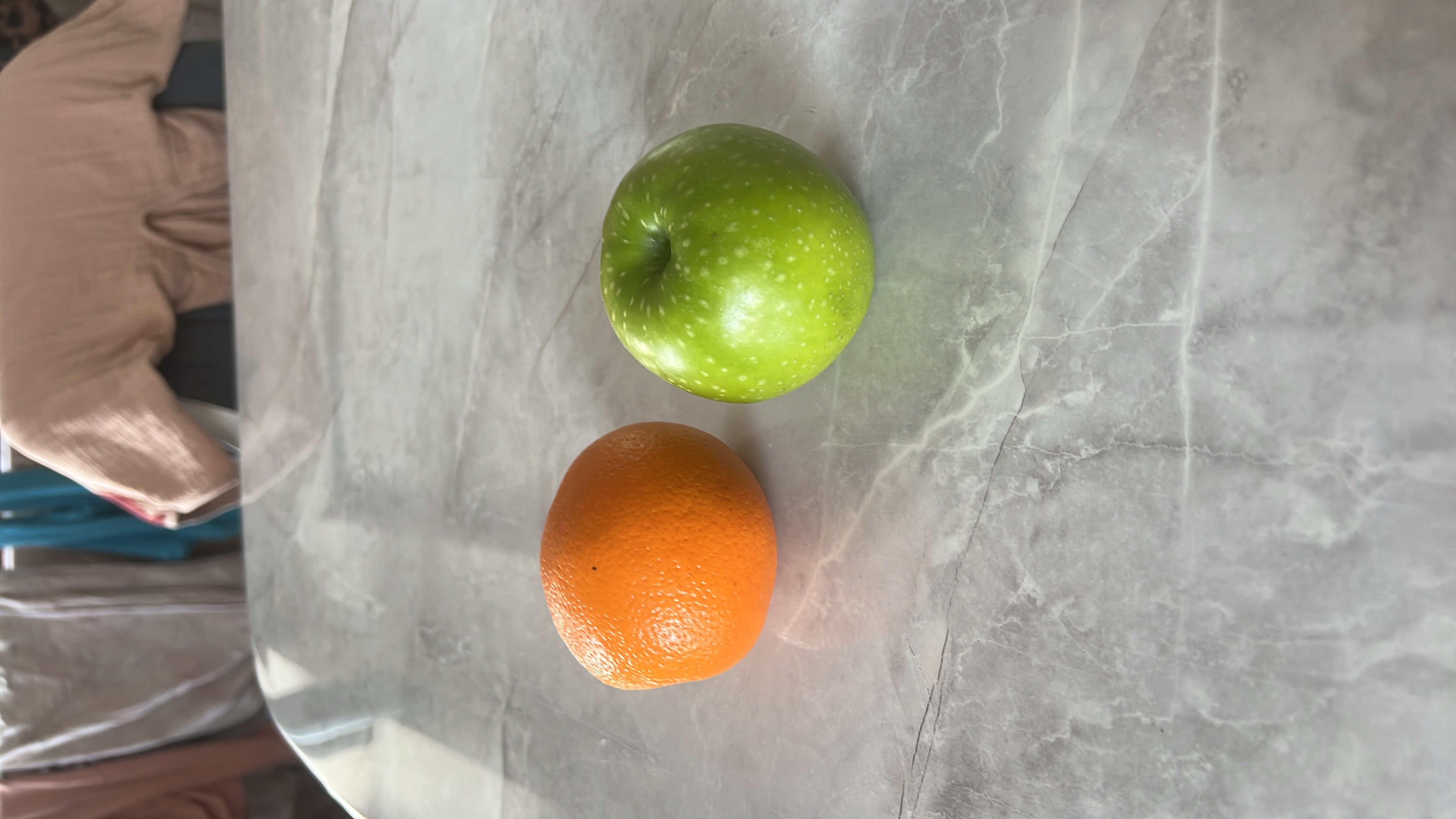The image shows an orange and a green apple, both of which are nutritious fruits rich in vitamins and low in fats.