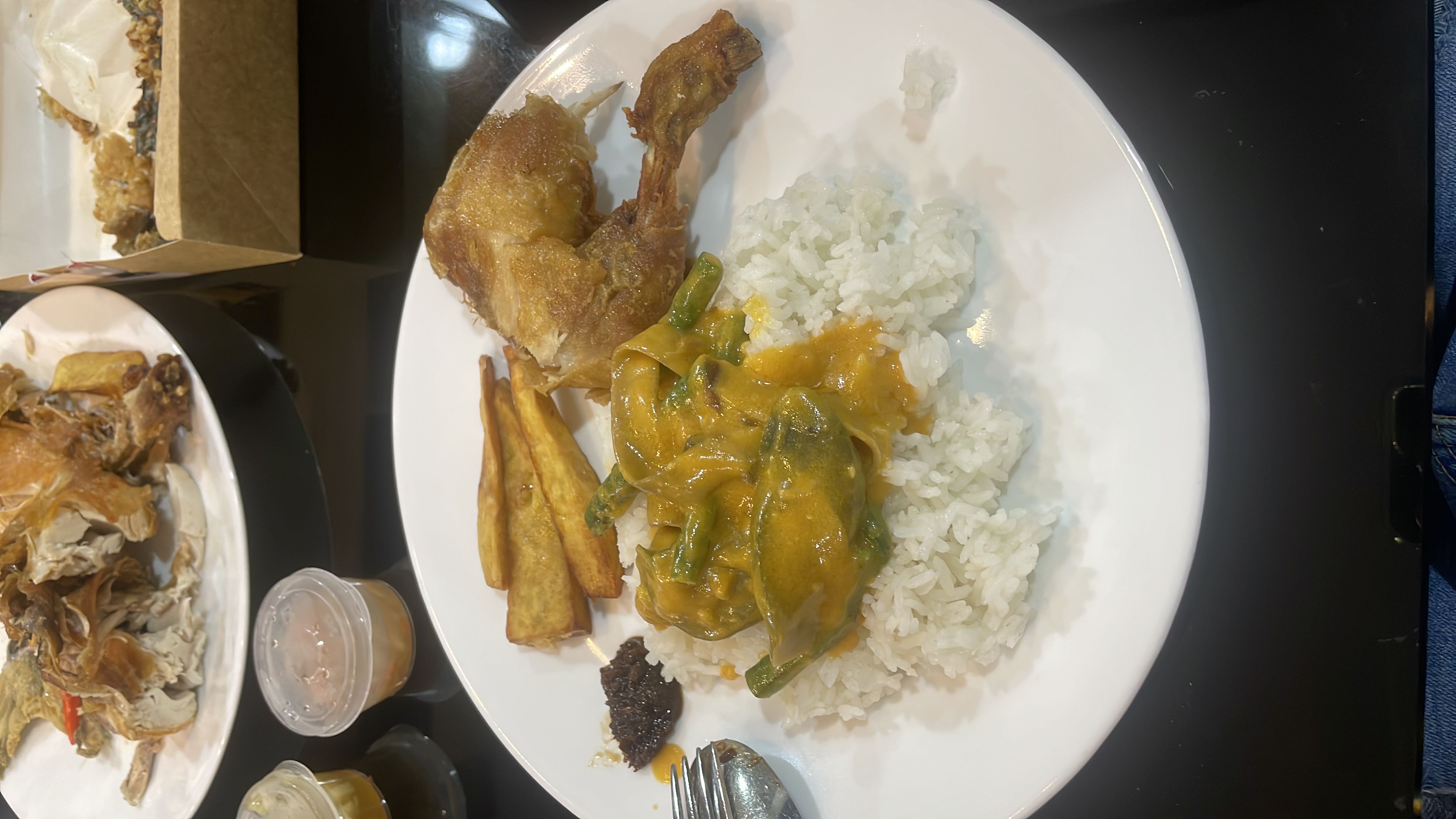 A meal consisting of rice, fried chicken, vegetables in a creamy sauce, and fried sweet potatoes.