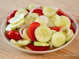 A fresh vegetable salad containing cucumbers, tomatoes, onions, and a light dressing.