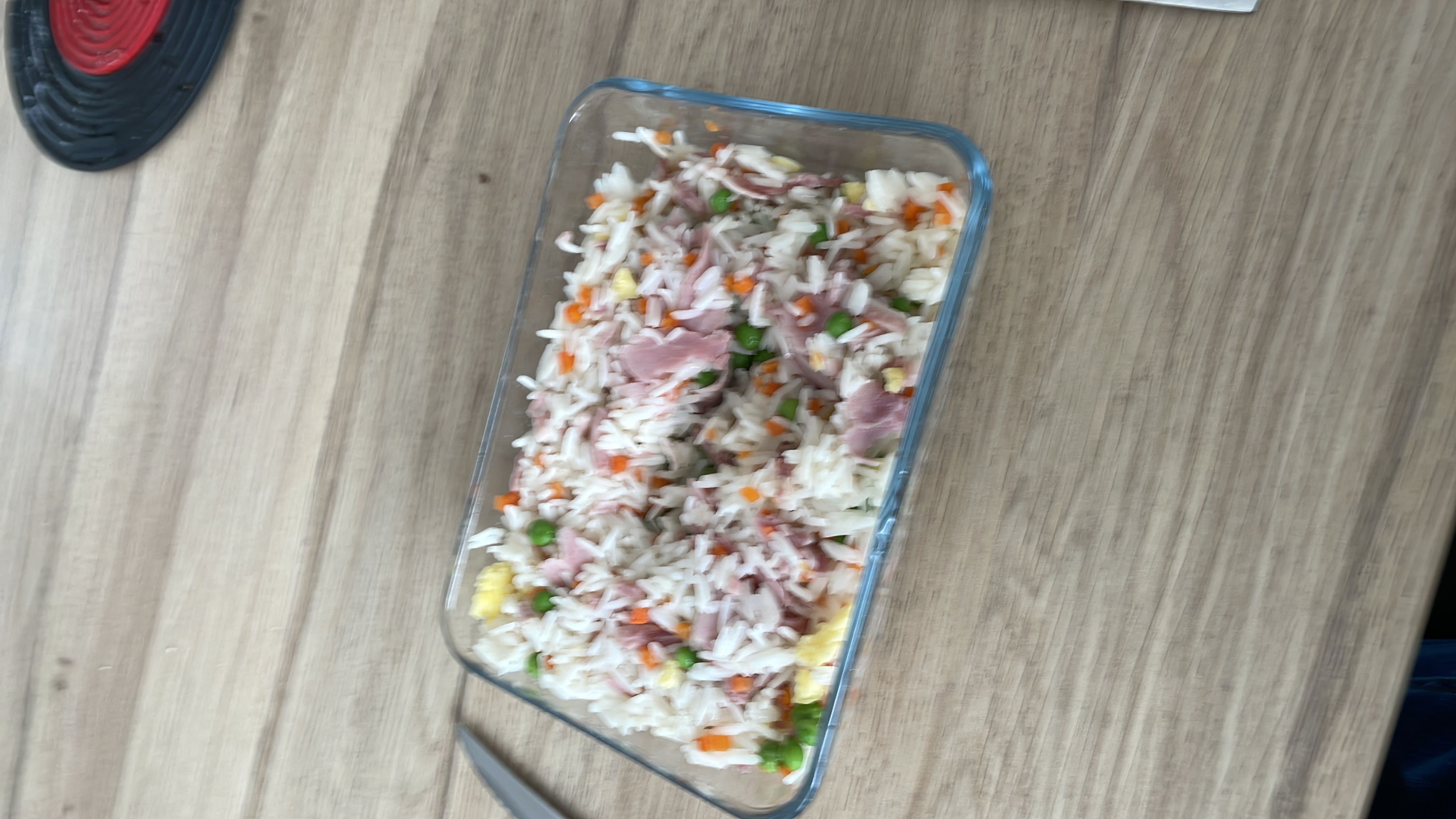 A dish of fried rice mixed with ham, peas, carrots, and scrambled egg, providing a balanced mix of protein, carbs, and fats.