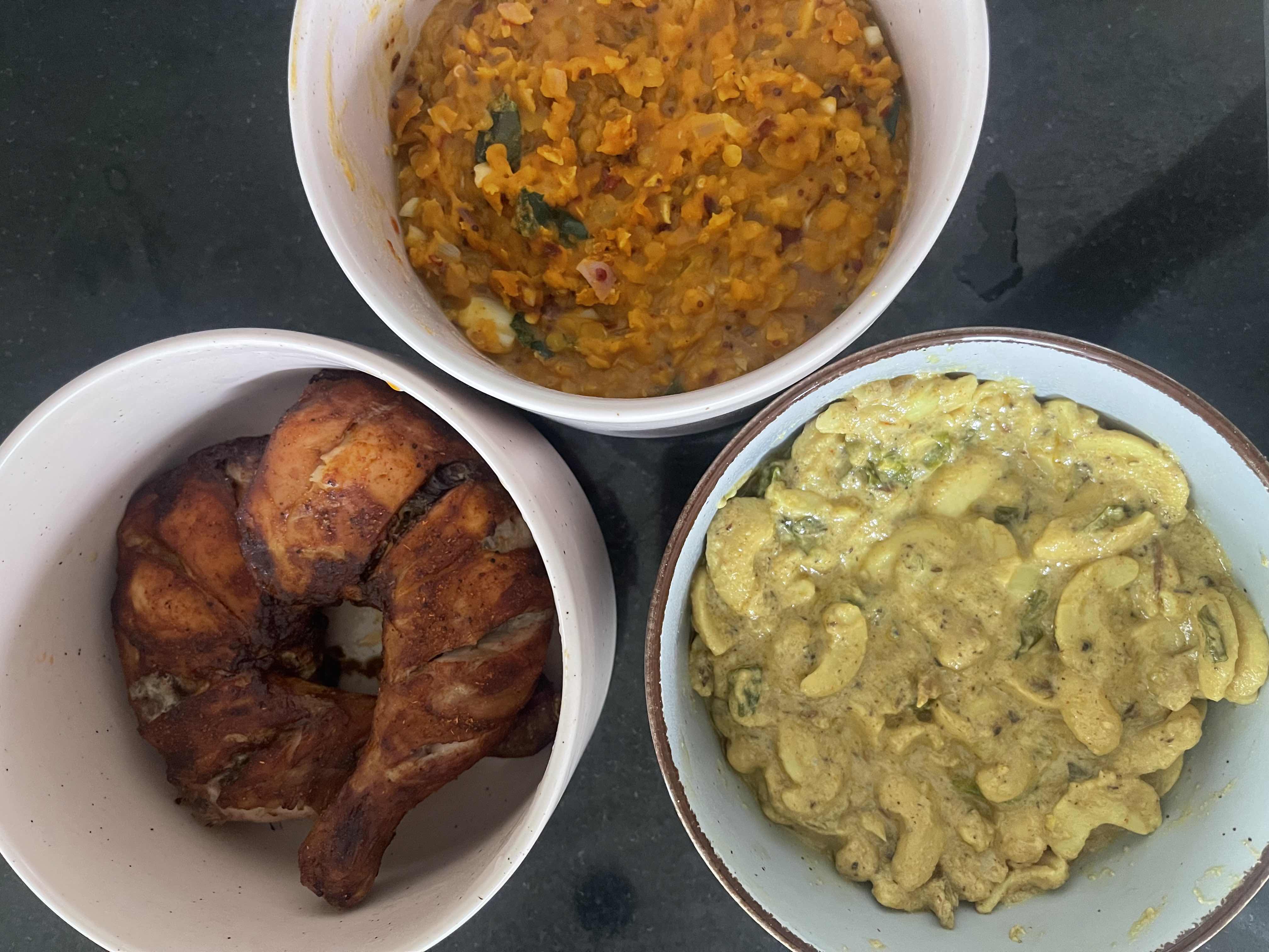 The image shows a meal consisting of grilled chicken, lentil curry, and cashew curry, providing a balanced mix of protein, carbs, and fats.