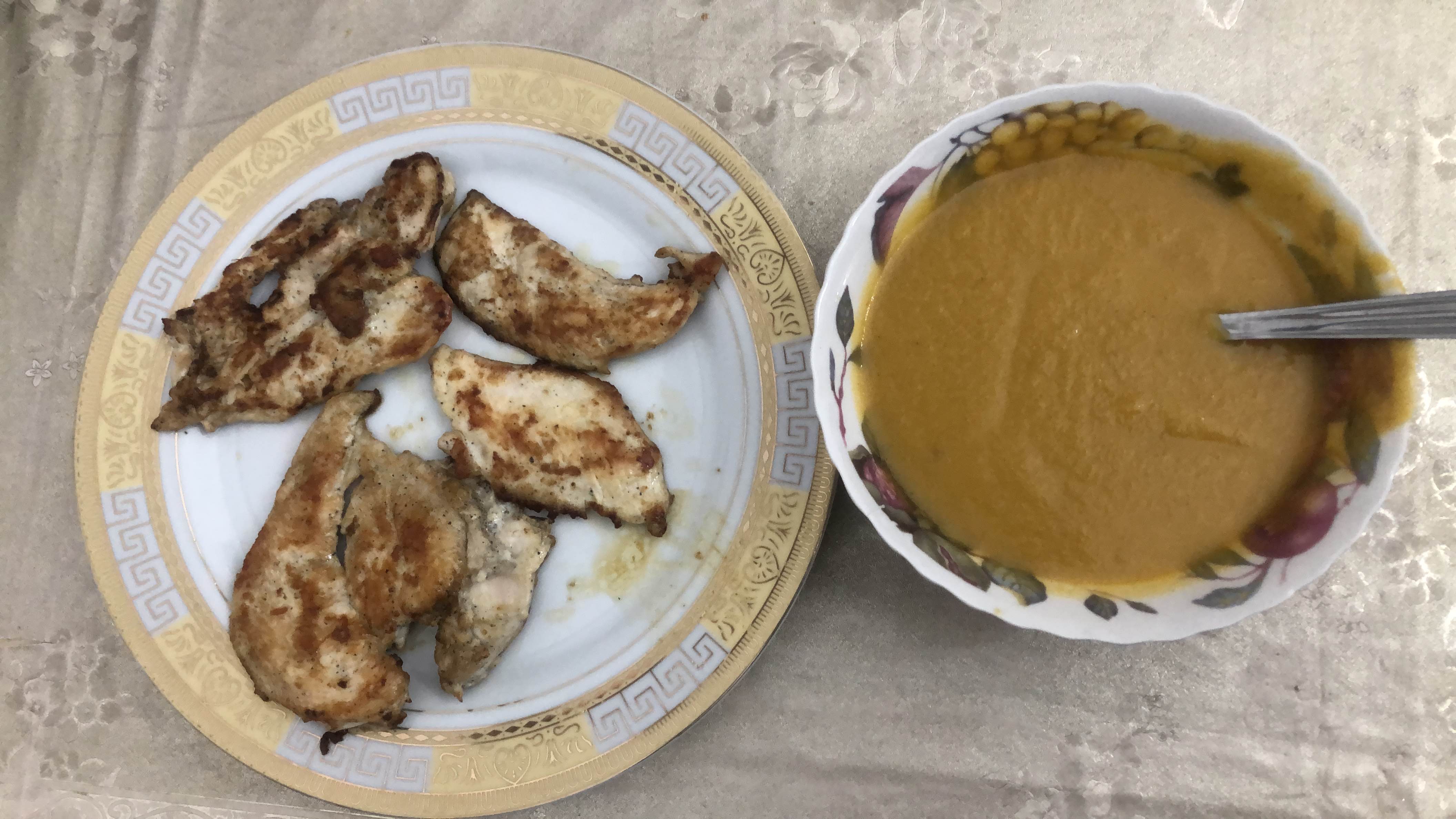A meal consisting of grilled chicken and a bowl of vegetable soup, providing a balanced mix of protein, carbs, and fats.