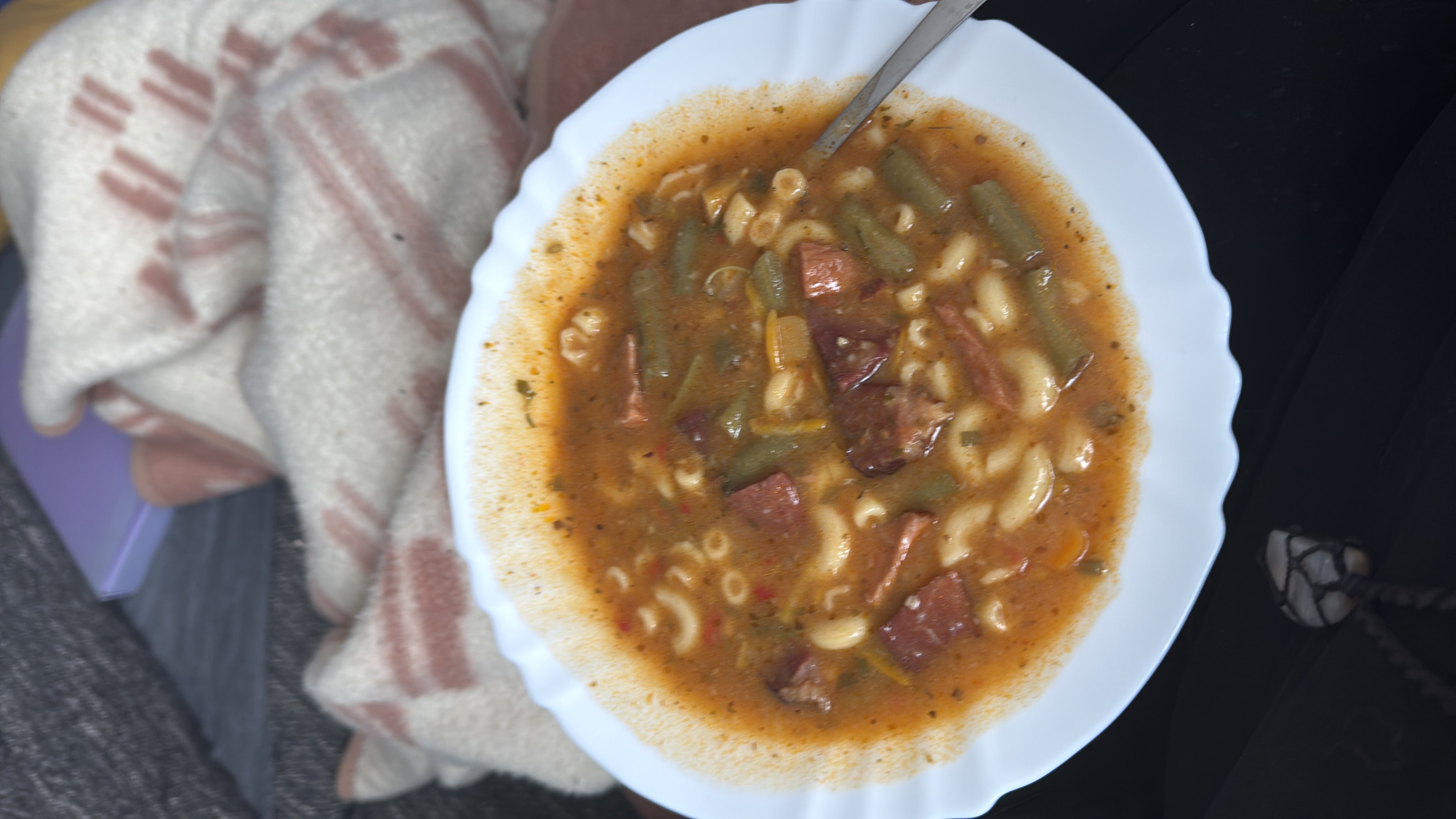 A hearty soup with macaroni, green beans, sausage, and a tomato-based broth.
